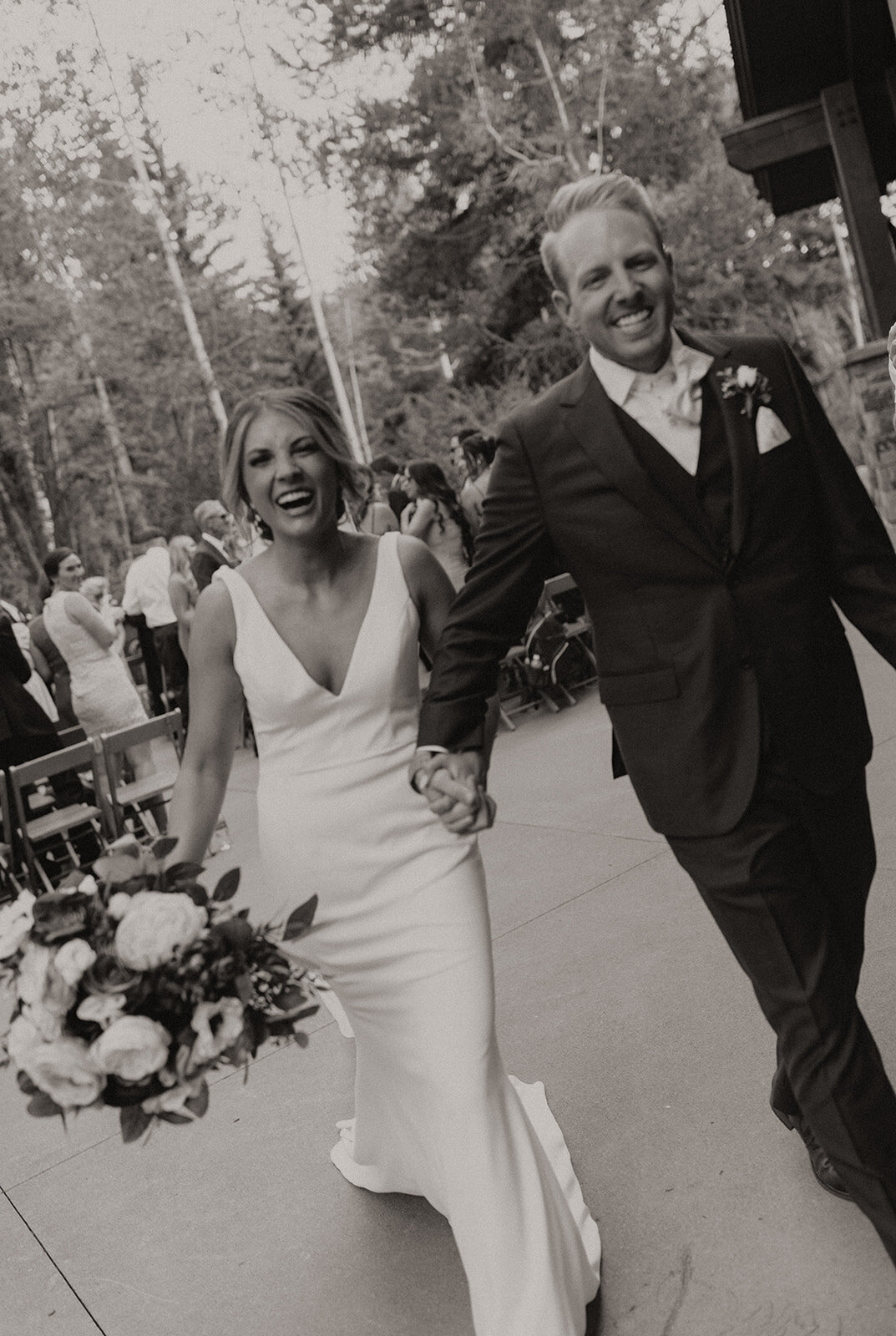 Black and white photo of bride and groom happily walking to their reception