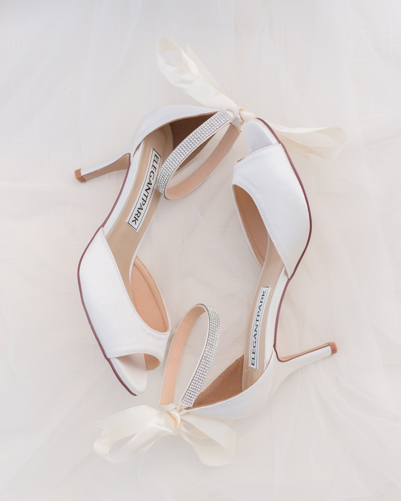 close up of brides shoes laying on side with veil in the background