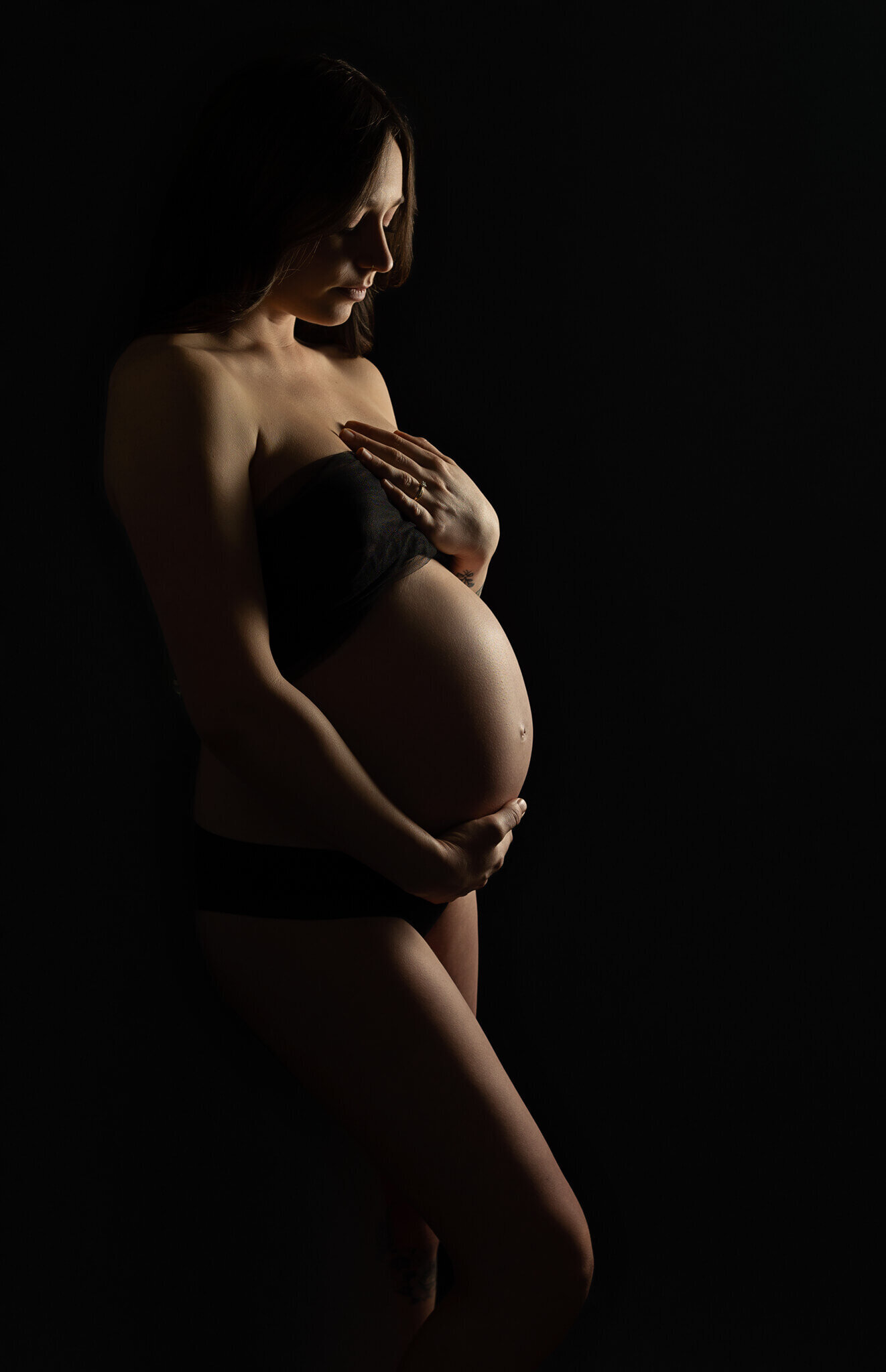 silhouette of a pregnant woman while touching her belly and looking down in a beautiful and artistic way