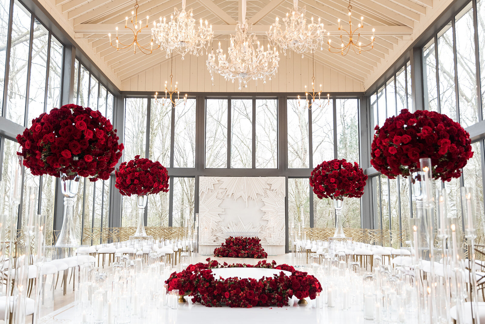 Romantic luxury wedding ceremony at Mallard’s Croft featuring red rose floral arrangements, crystal chandeliers, white modern aisle, and elegant event design by Wells Design Co.