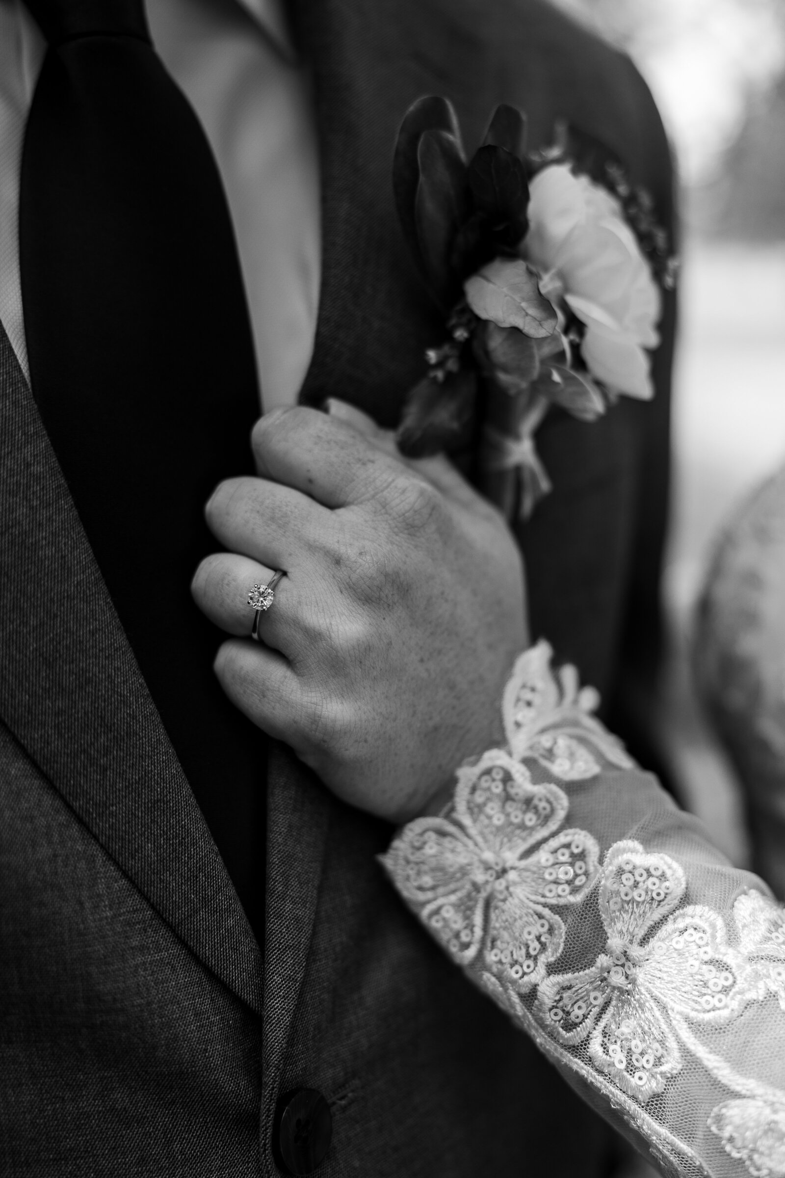 Black and white close-up of the bride gently holding the lapel of the groom’s jacket at a Ridgway State Park wedding.