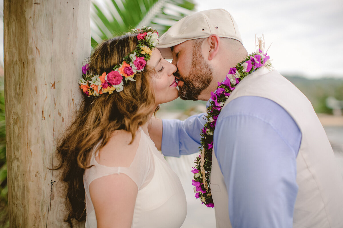 bride and groom kissing with flower garlands