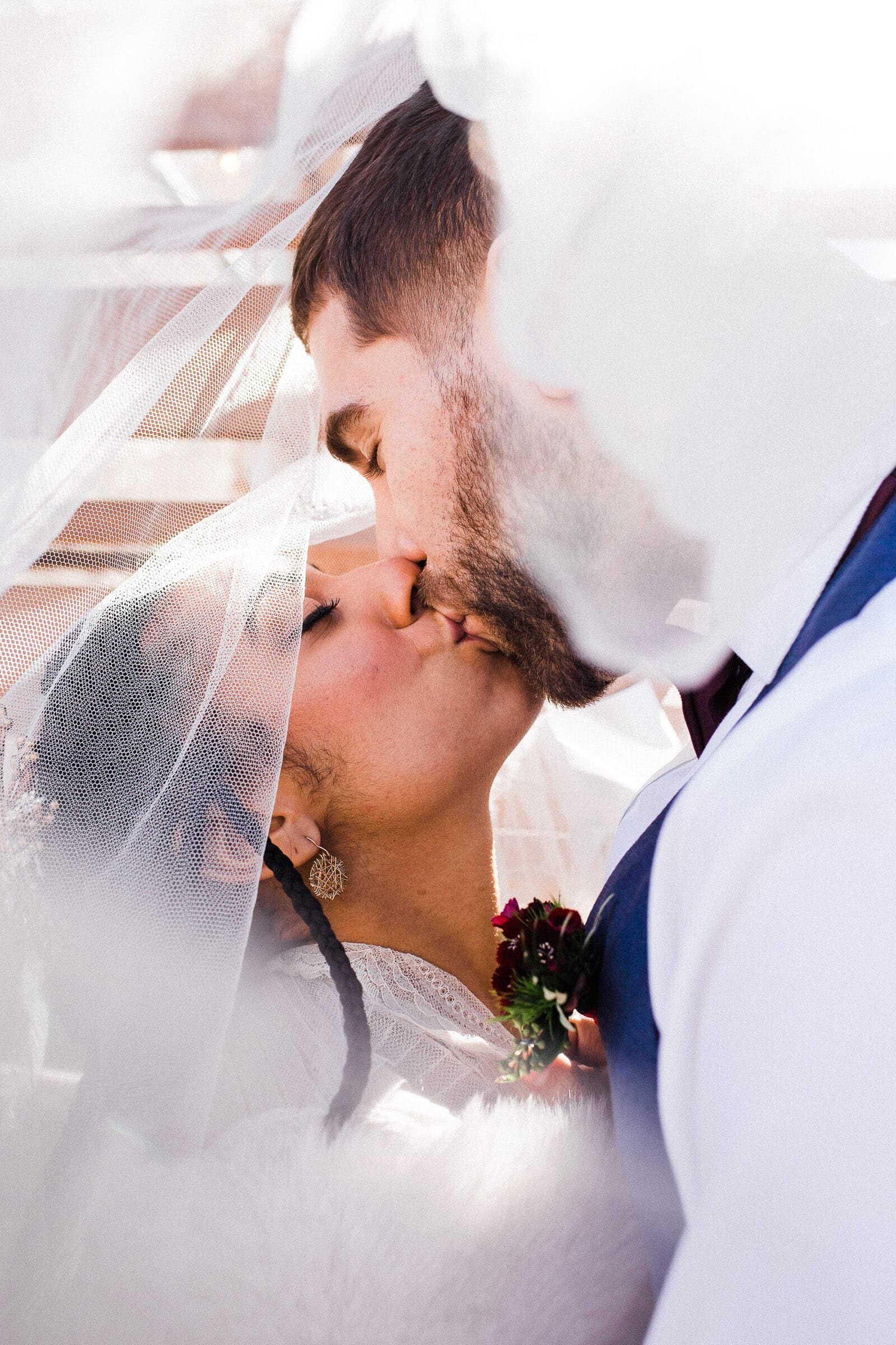 Bride and groom first kiss under veil in PNW