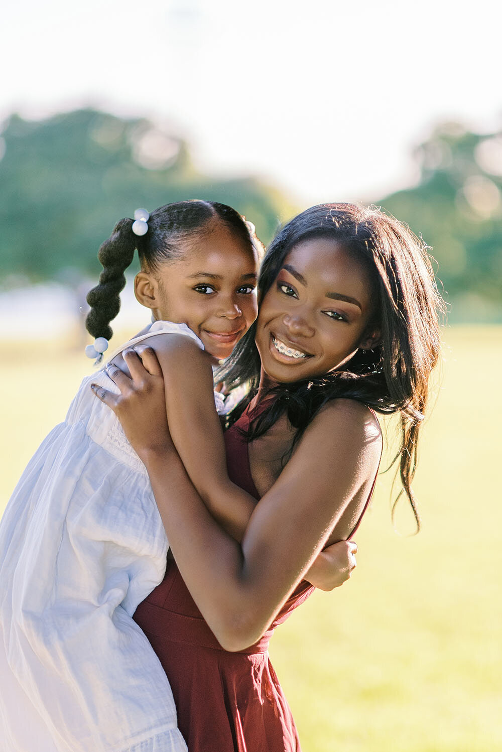 Teenage girl in a red dress hugging her younger sister in her Chicago family photos