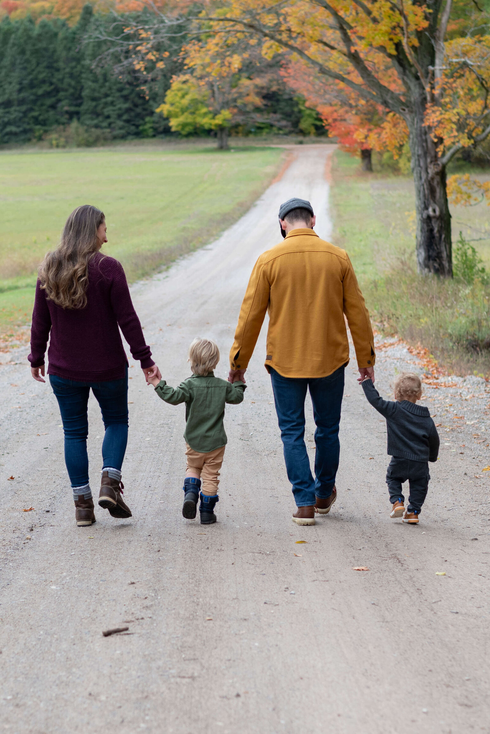 family walking down gravel road holding hands