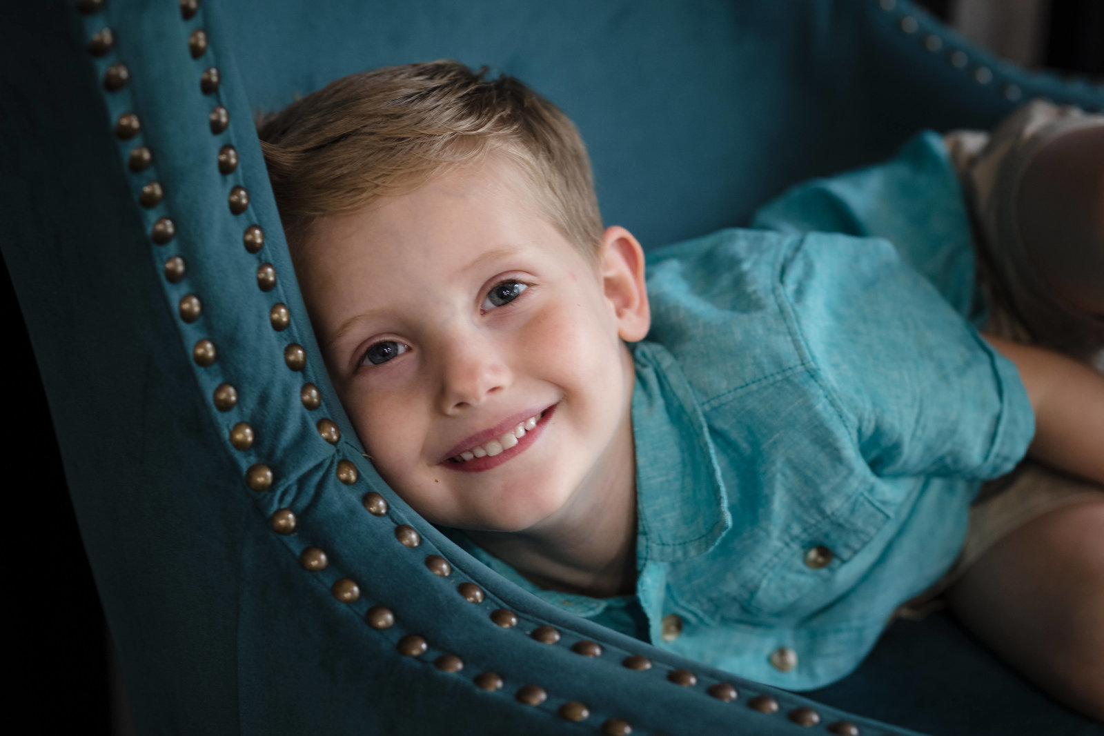 Young boy smiling playfully on chair