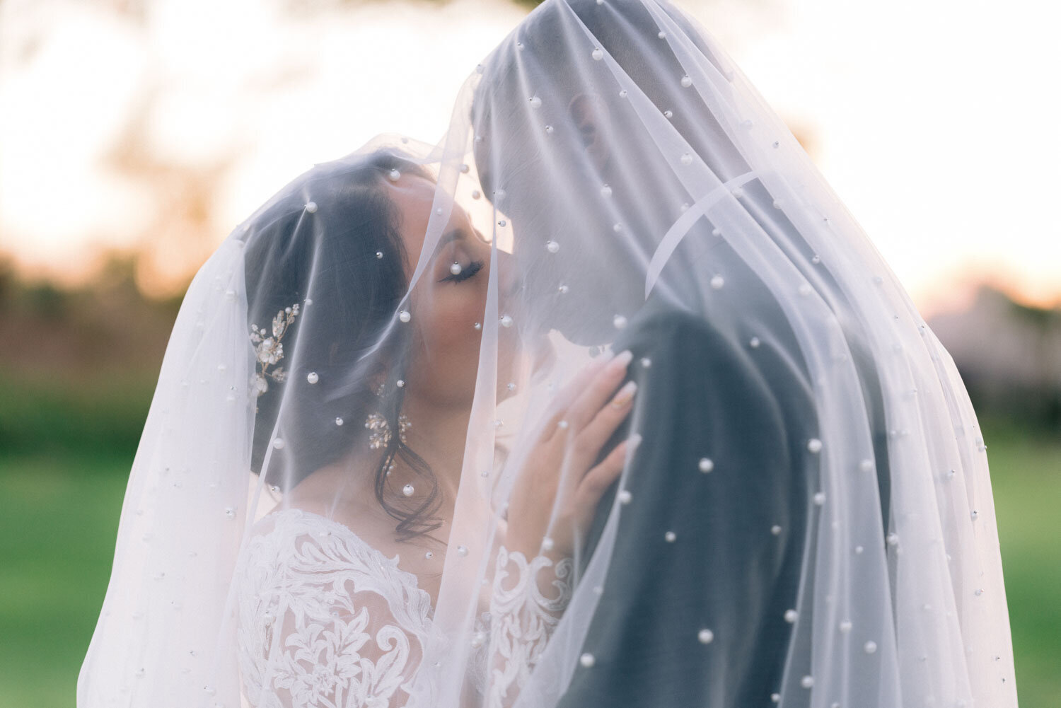 Bride and groom kissing under a veil