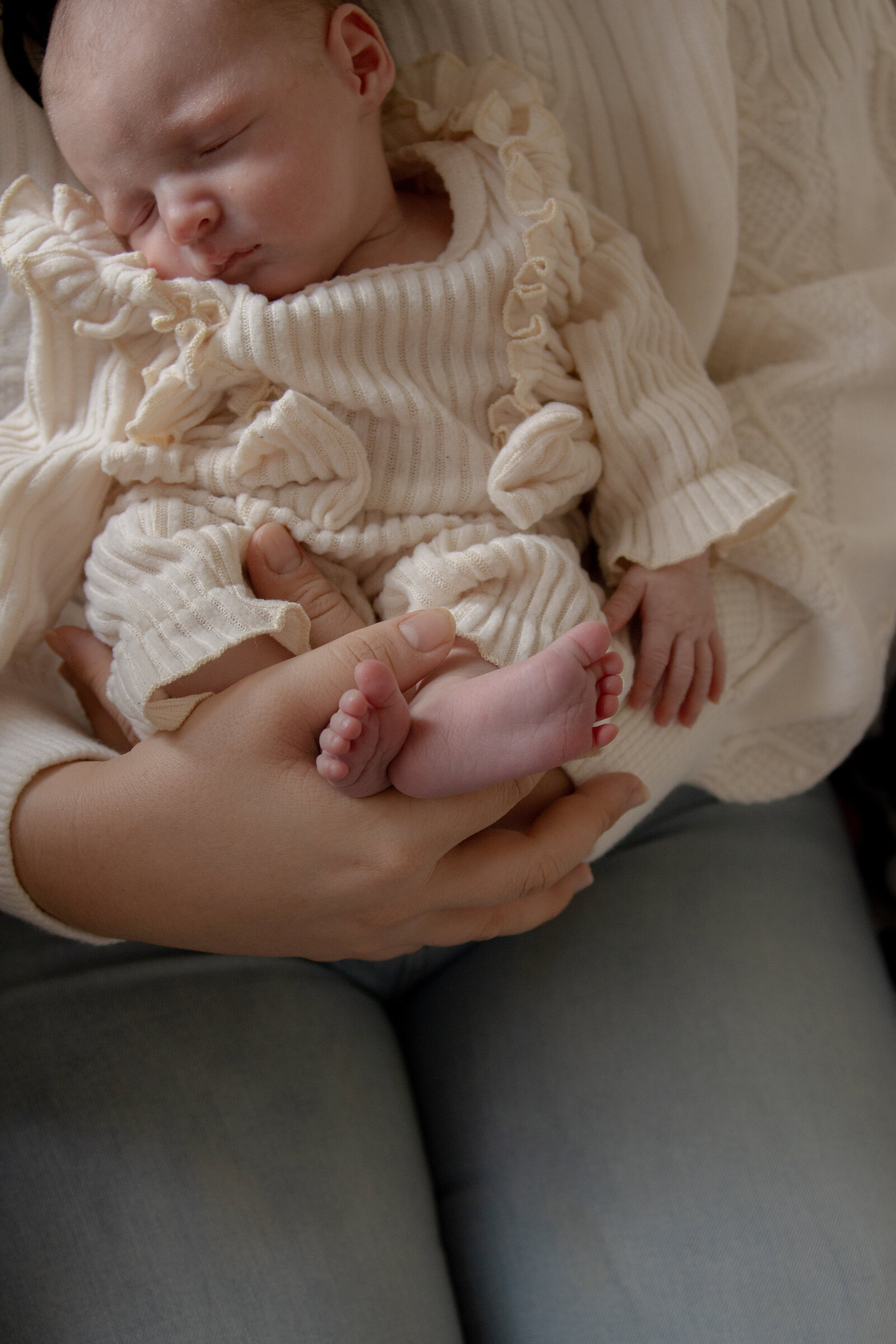 mother holds newborn daughter with focus on tiny feet