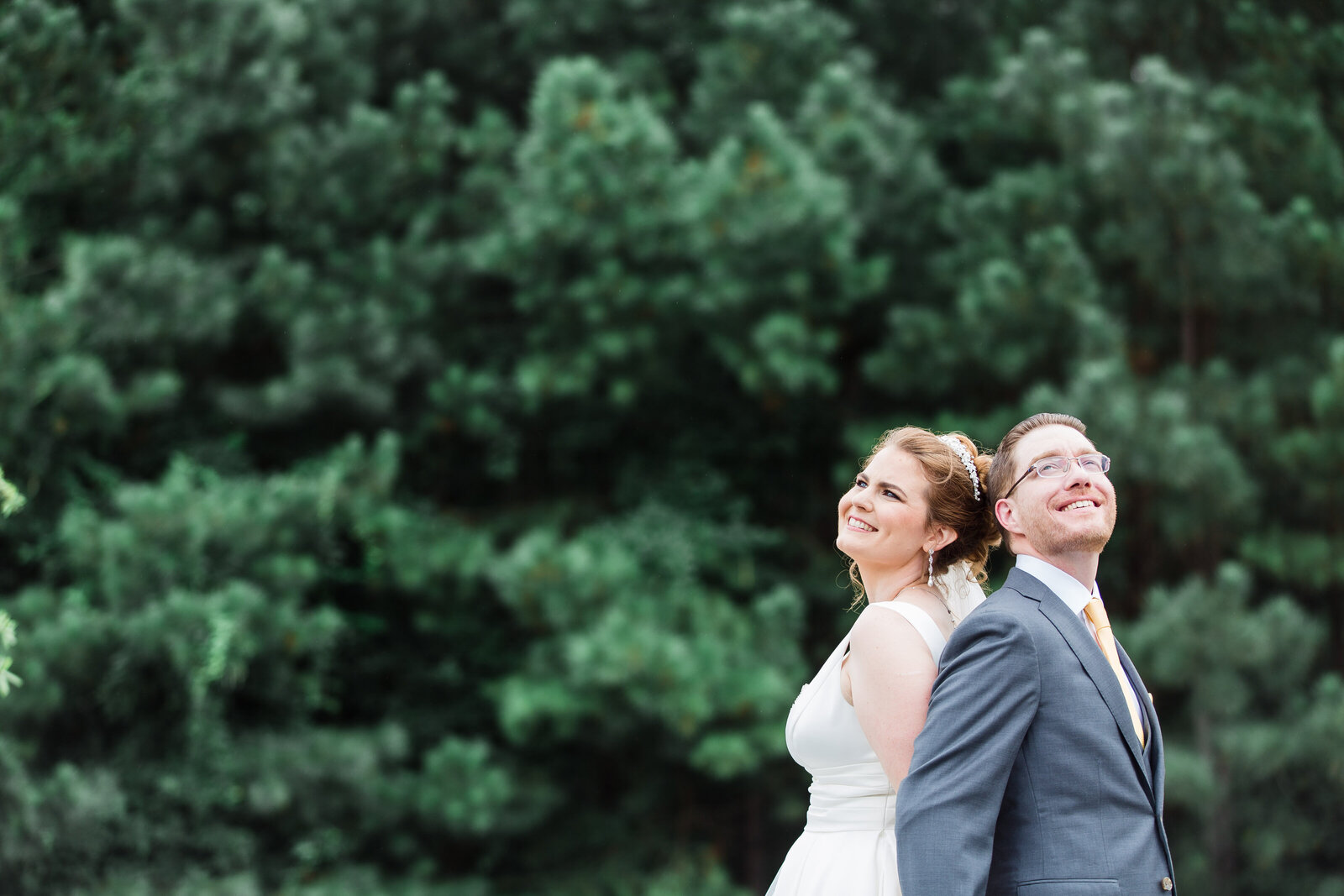 A bride and groom standing in front of a forest.