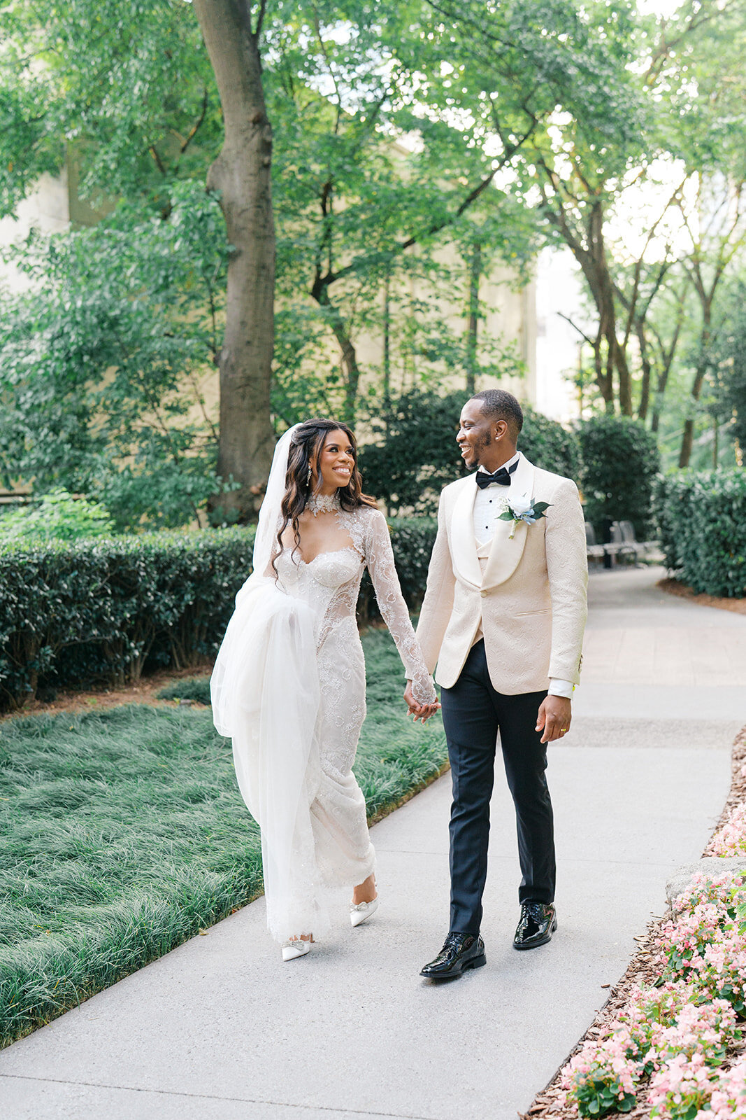 African American Bride and Groom walk on the sidewalk beside Wimbish House during cocktail hour on their wedding day