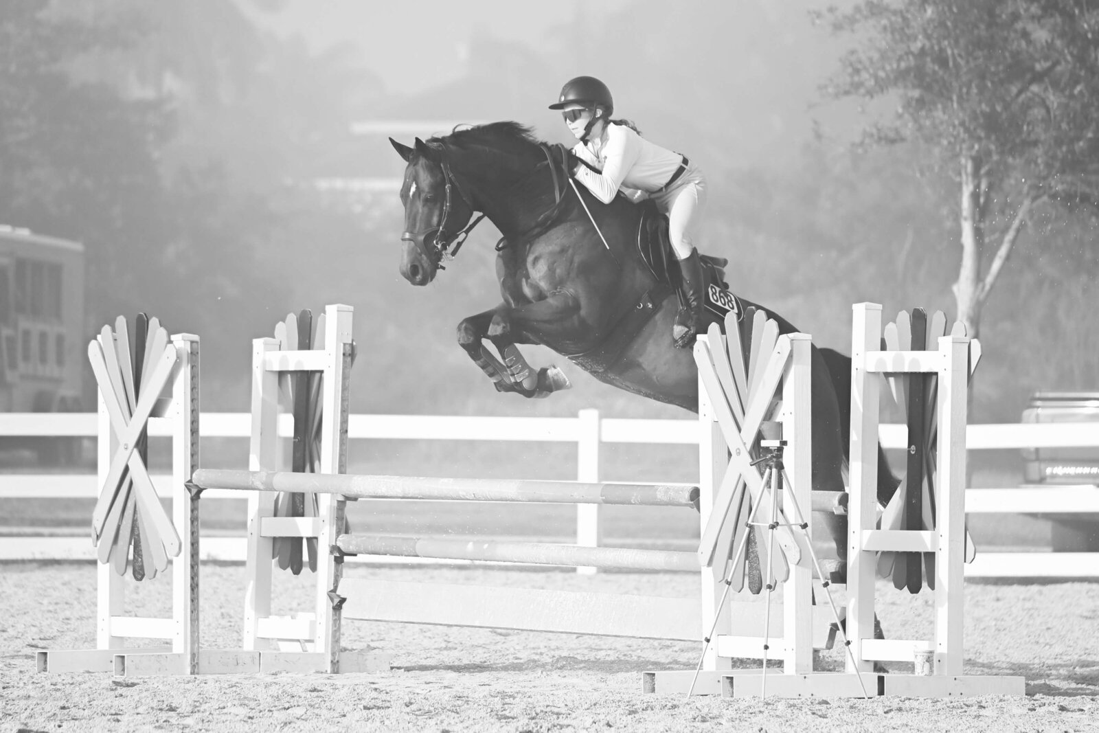 heritage horse show photography of a rider jumping over a fence with the fog closing in around them in black and white