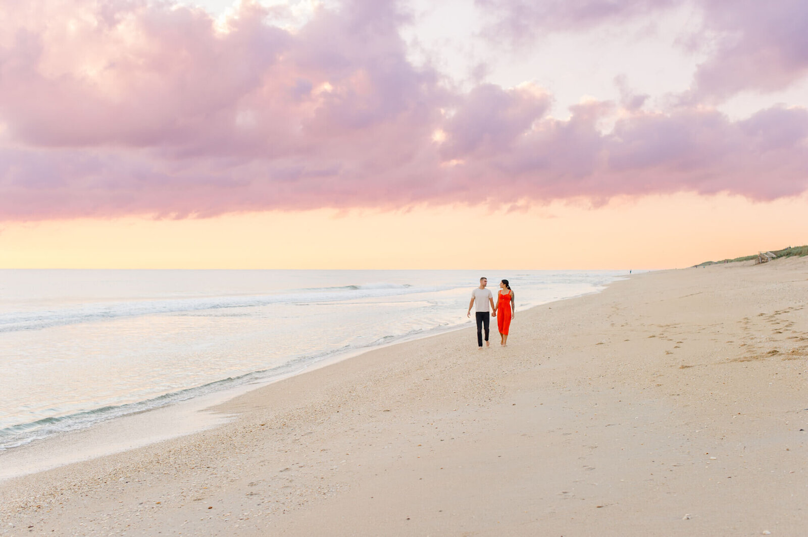 Orlando couple walks along the beach holding hands during their sunrise proposal photographer session
