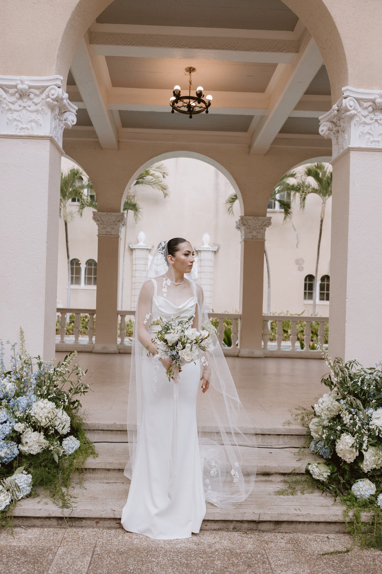 Bride standing inf ront of pillars at cafe julia with flowers surrounding her
