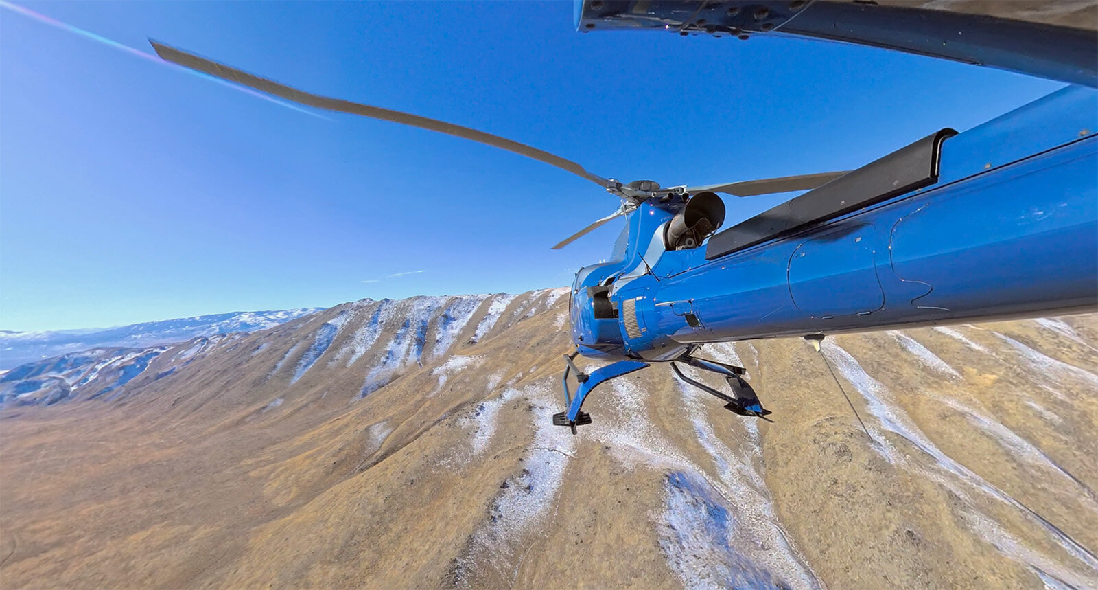 Blue helicopter flying above scenic mountains nevada