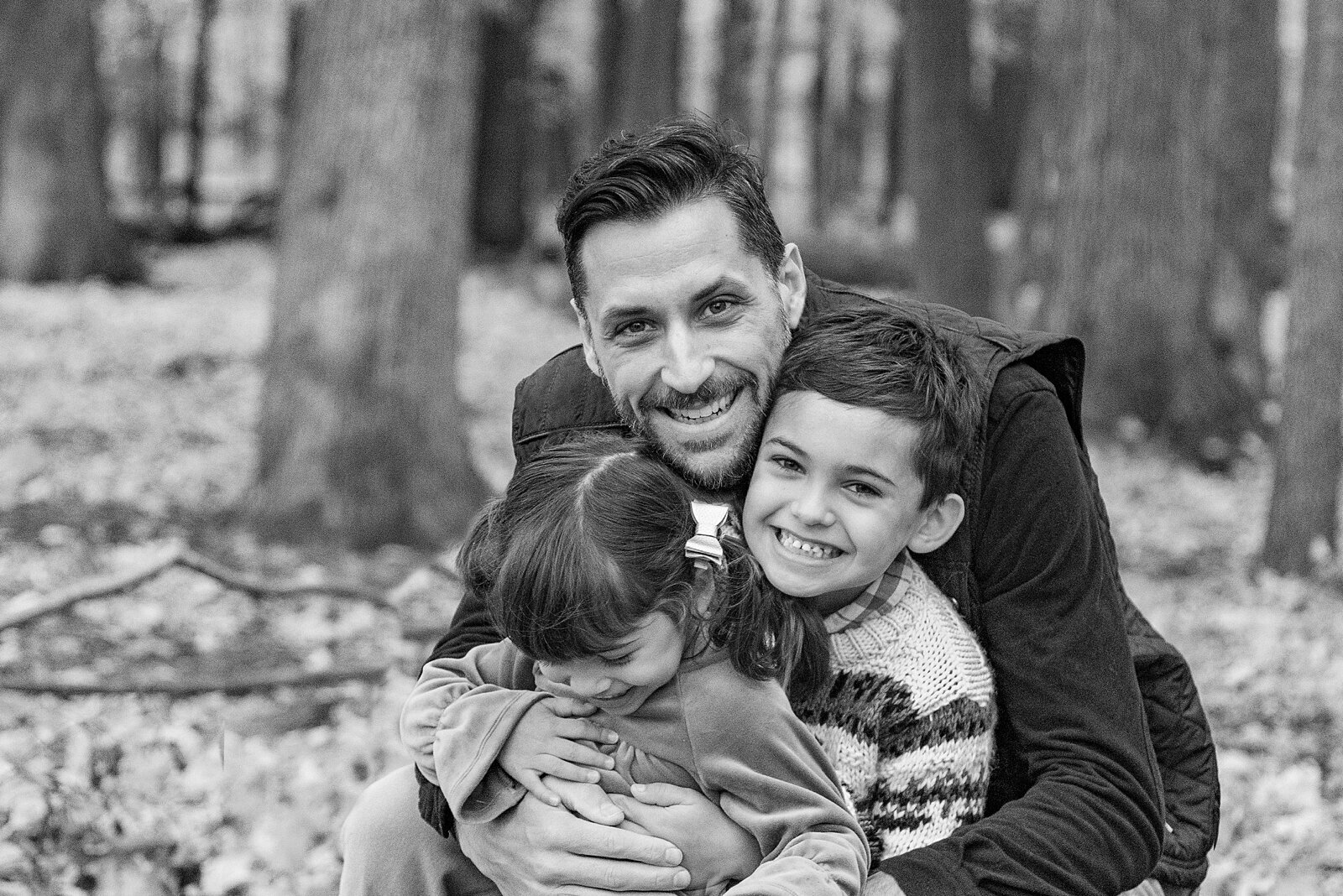 black and white photo of a Dad hugging his two young children