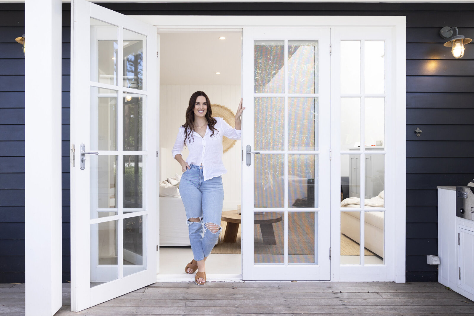 Lady standing in doorway wearing jeans and a white shirt