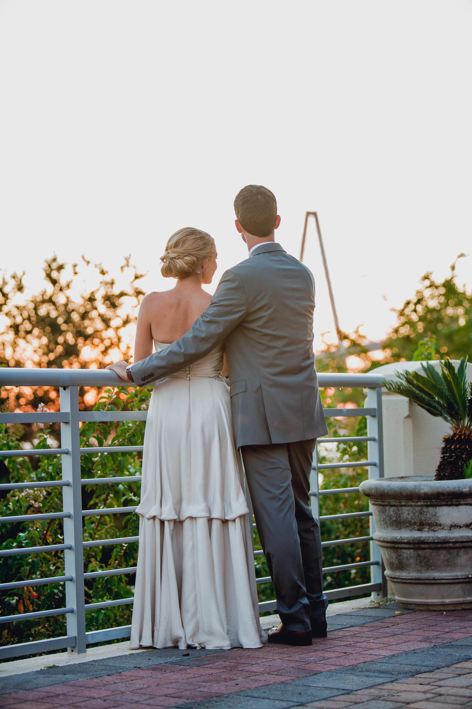 Bride and groom pose at sunset with Ravenel Bridge in background, Harborside East, Mt Pleasant, South Carolina