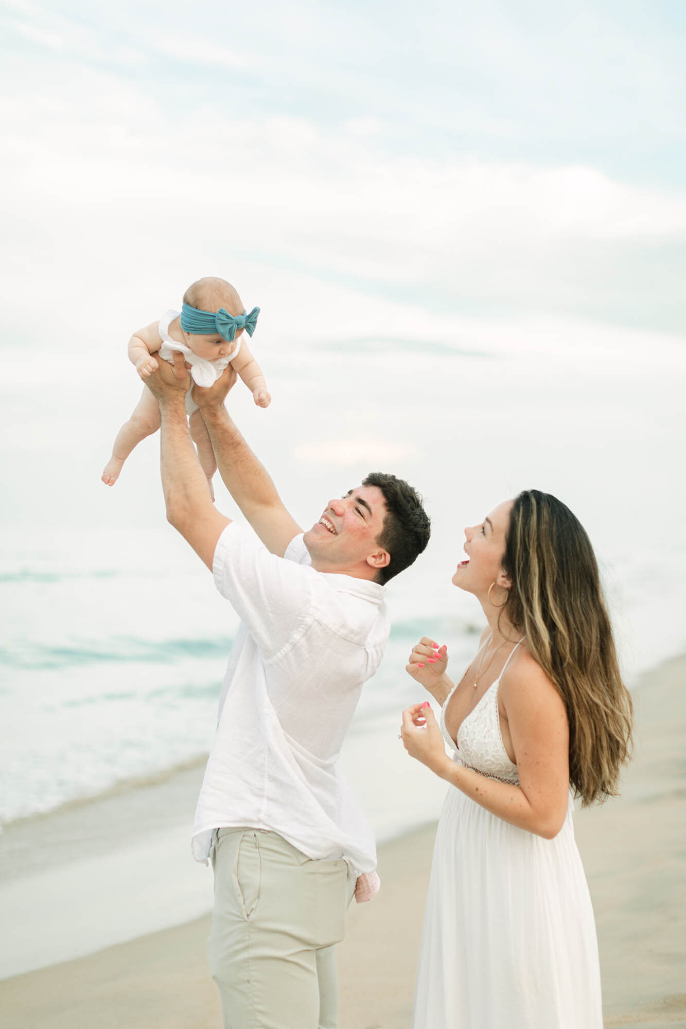Family photo of a dad lifting  his baby and  a mom laughing taken by  the Outer Banks photographers