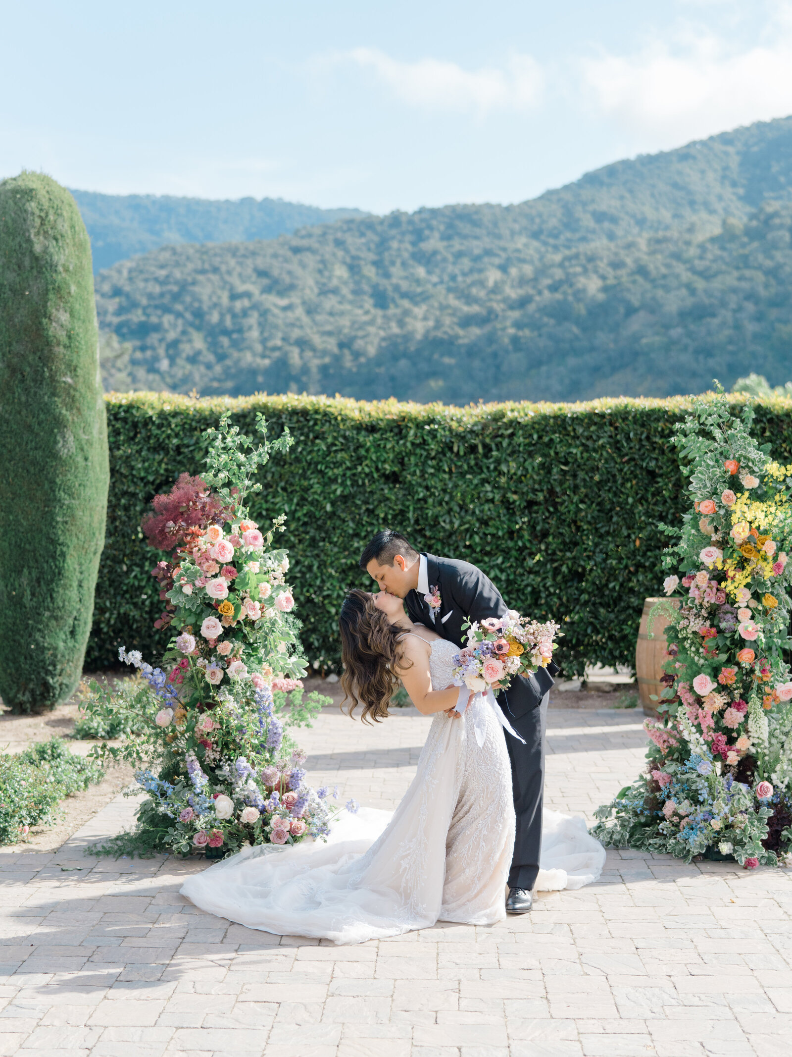 Groom dipping the bride and kissing her in front of beautiful hills
