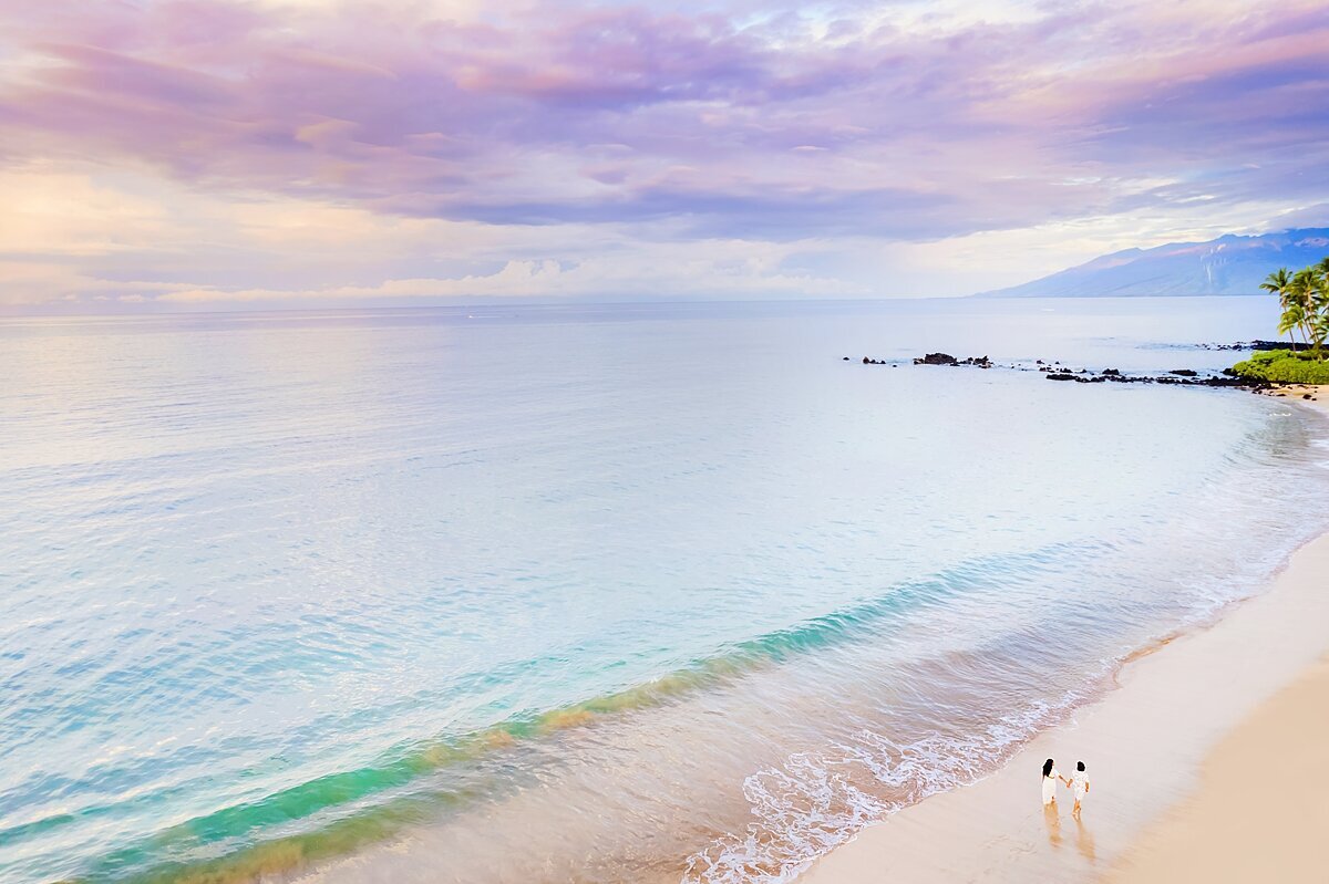 purple and pastel skies beyond a maui beach as the water brushes up against the shore