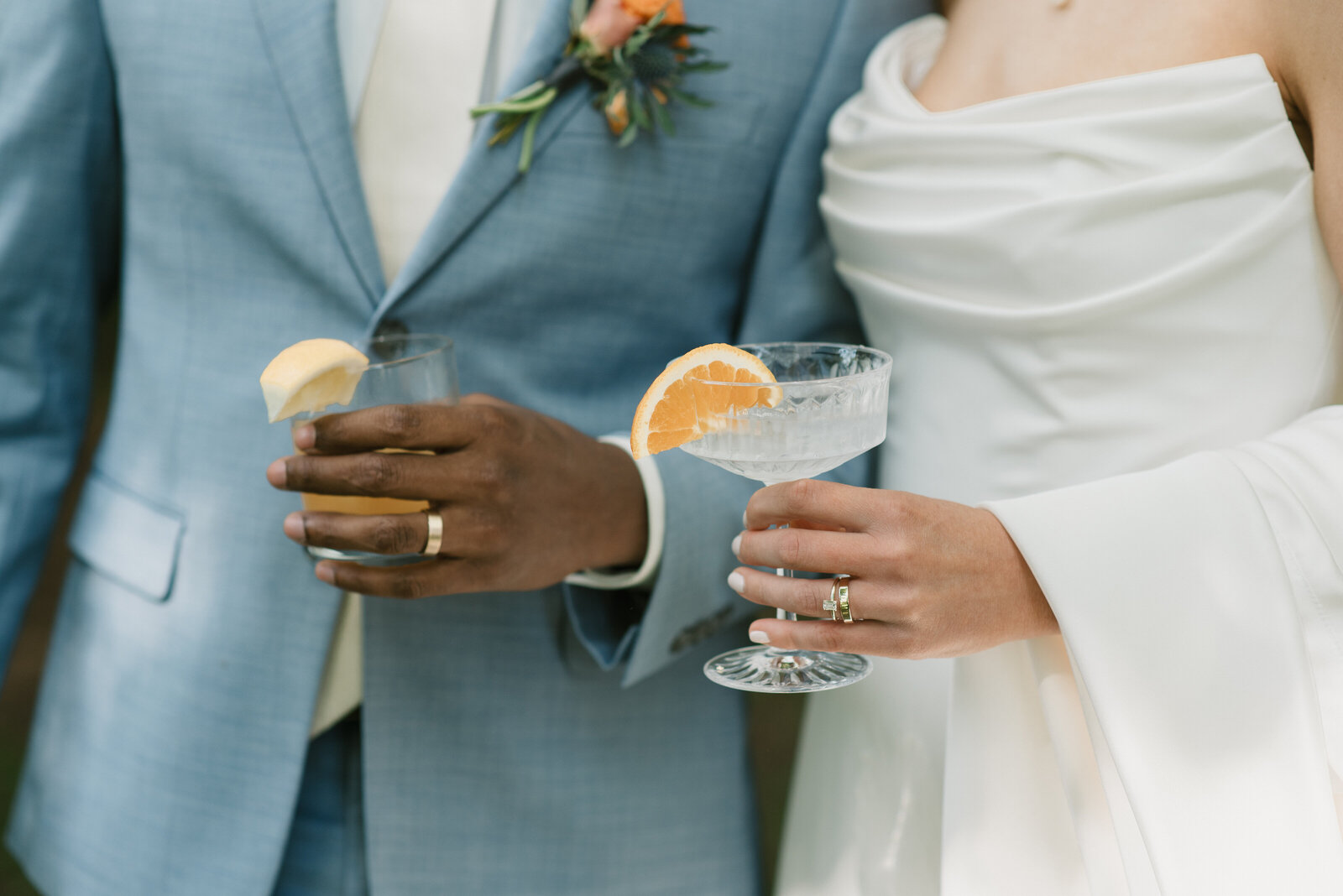 close up shot of bride and groom holding their cocktails with their wedding rings