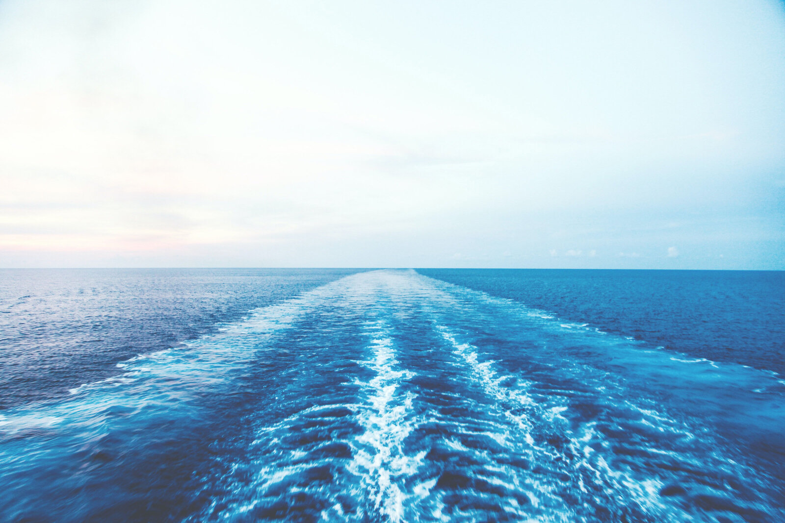 An ocean trail behind a cruise ship showing an expansive view of the ocean.