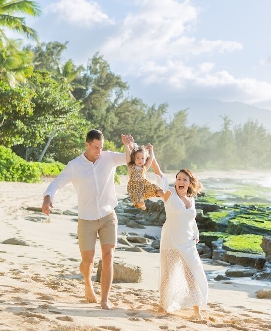 Mom and dad swinging daughter on the beach 
