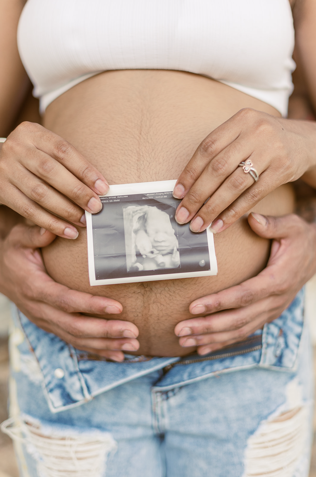 pregnant mother holding ultrasound photo in front of belly with dad holding belly too by york pa photographer