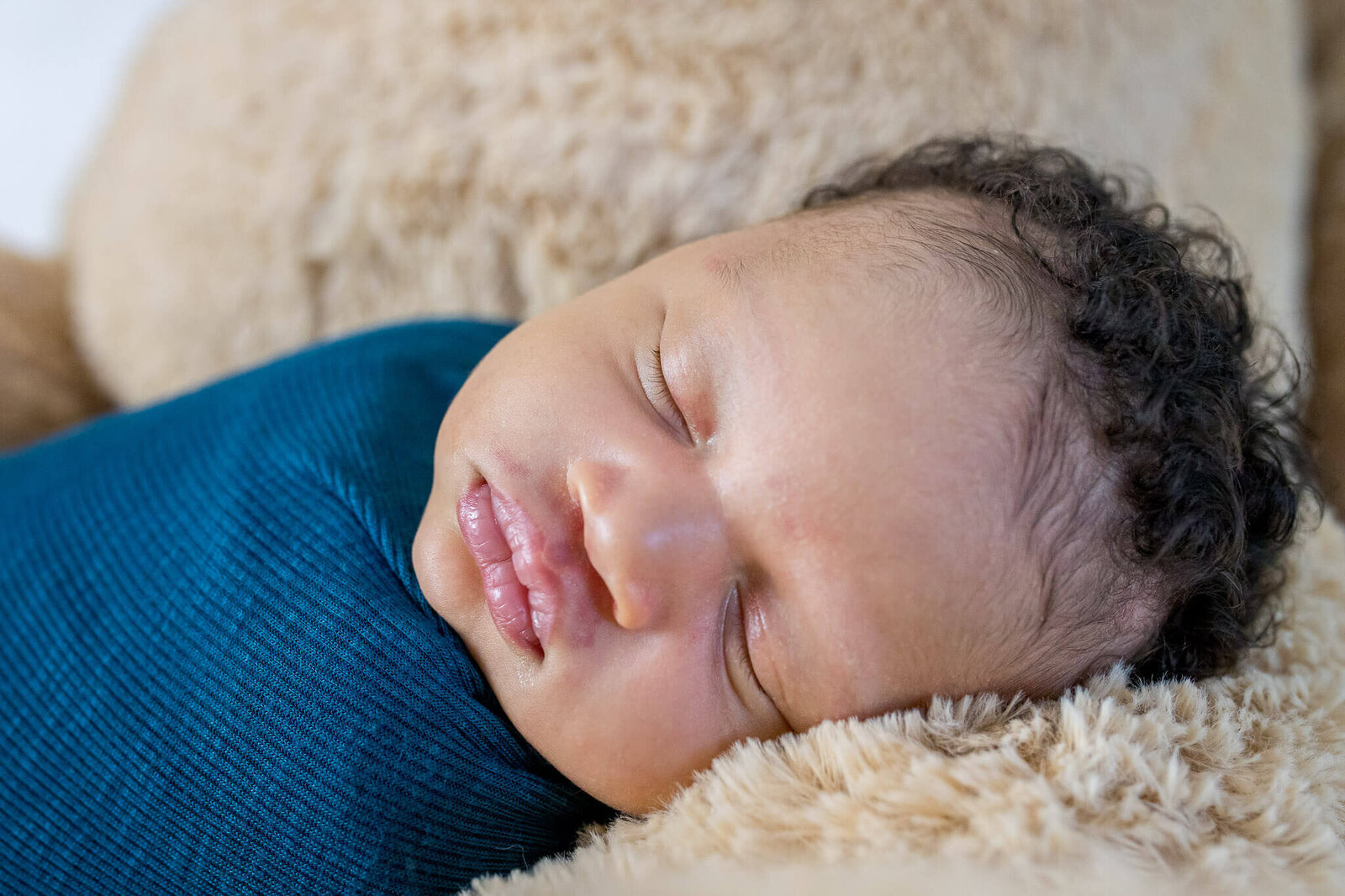 A close-up of a baby wrapped in blue  during his Woodbridge newborn photography session.