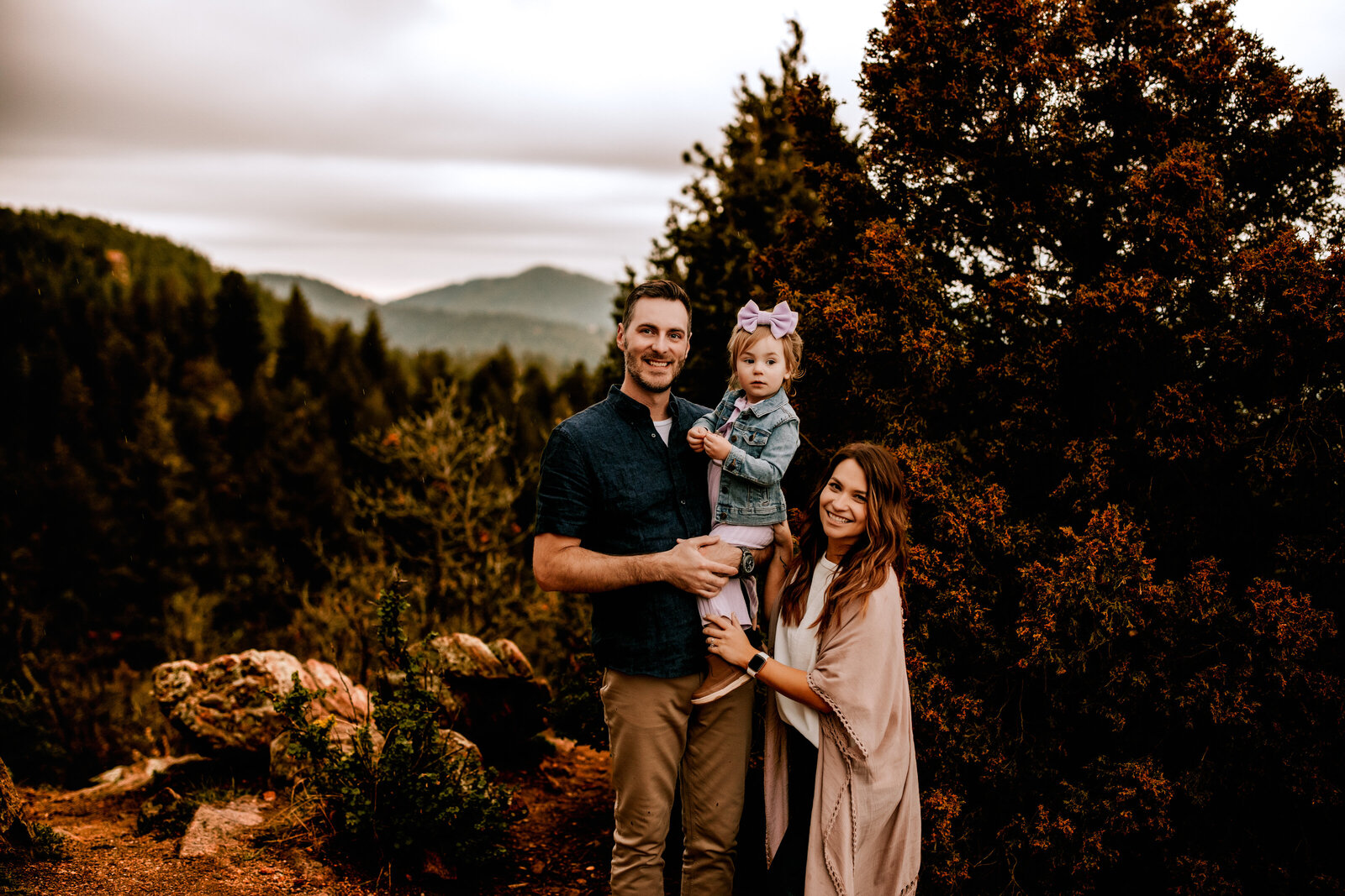 family of three posing on top of a mountain