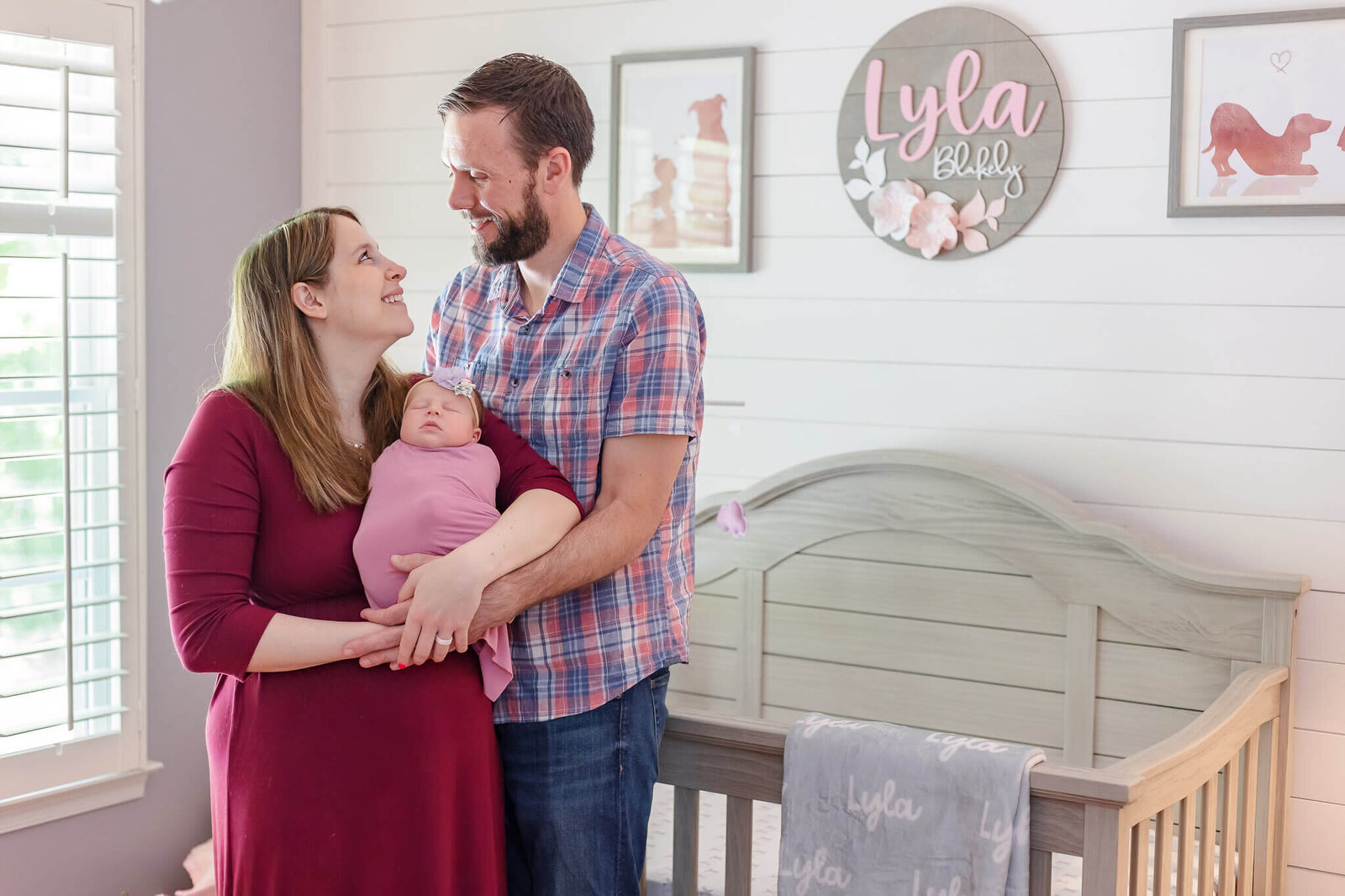 Mom and dad smiling at each other while mom holds the baby.