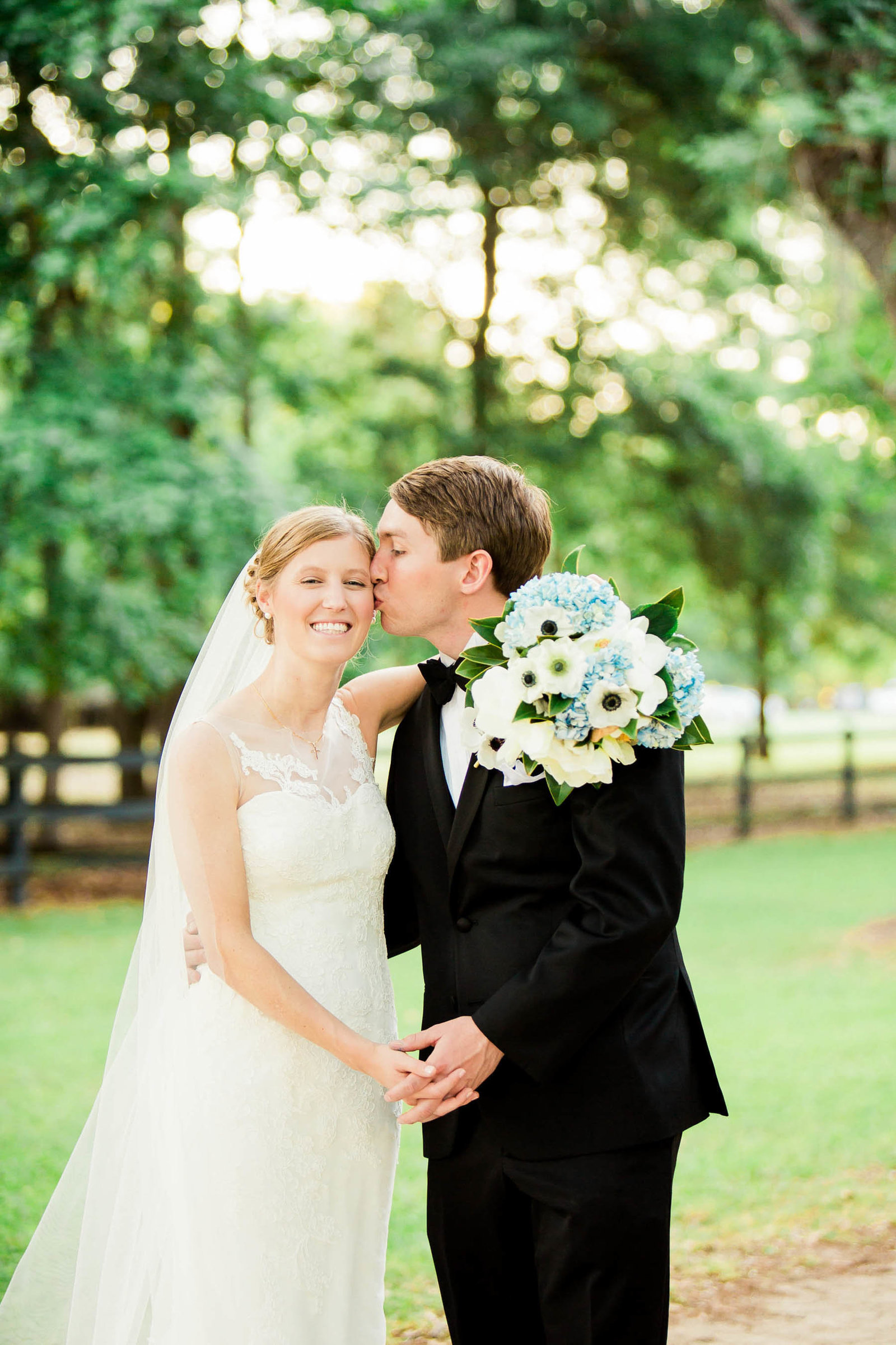 Bride and groom stand under avenue of oaks, Oakland Plantation, Mt Pleasant, South Carolina