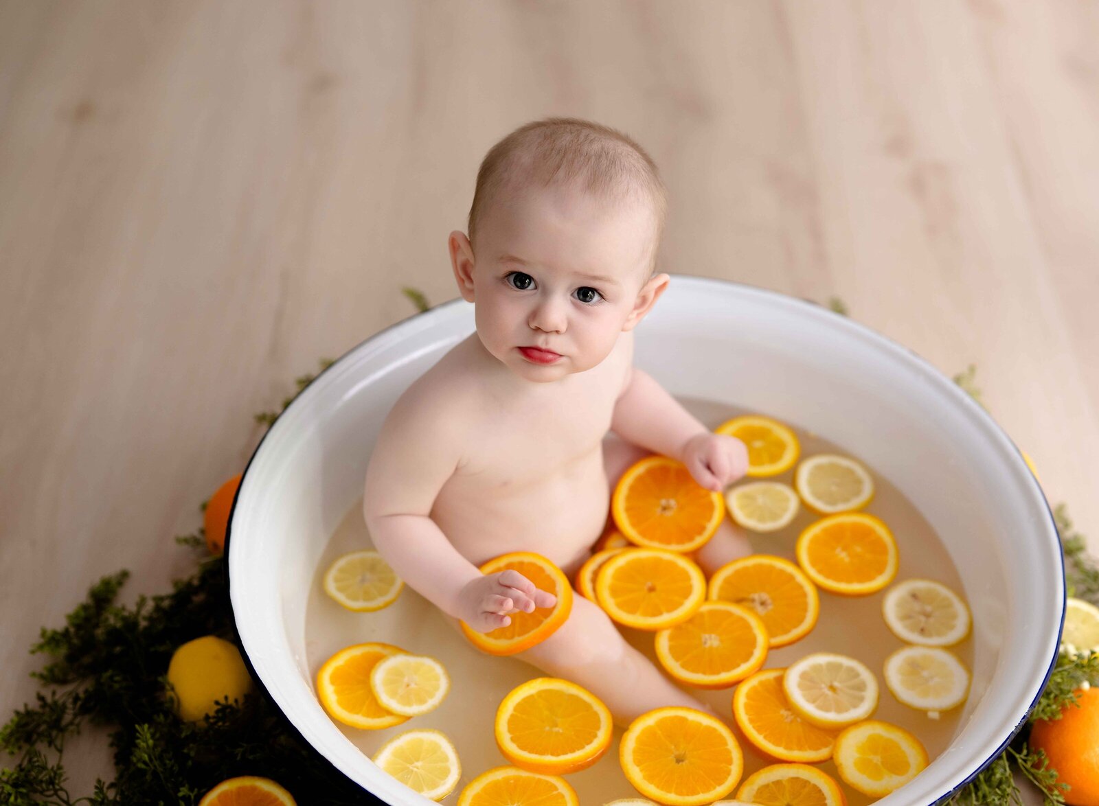 Baby sitting in basin tub with oranges and lemon slices in water. Baby Photo taken by Jenni Nikki Photography at Atlanta Photo studio.