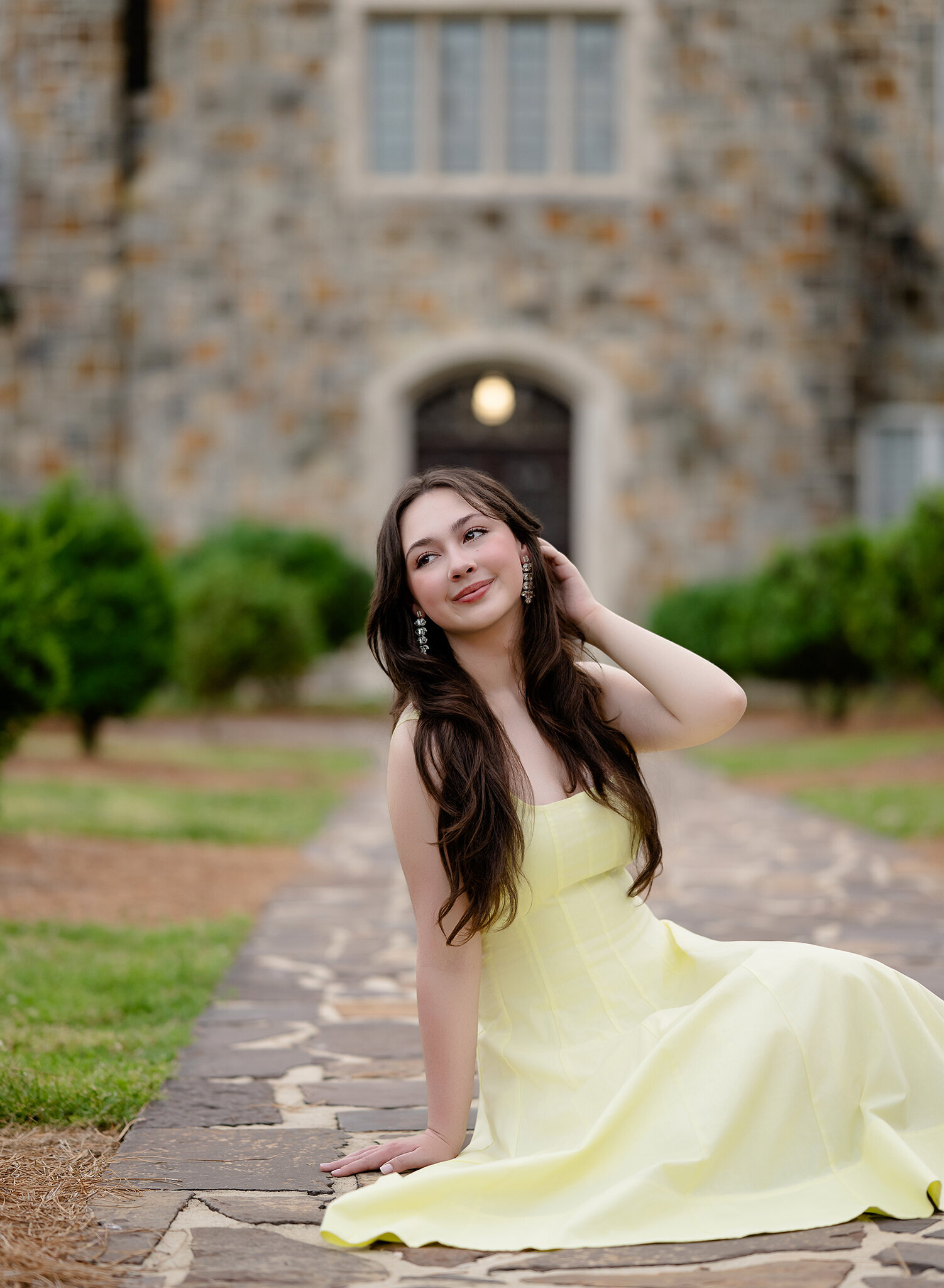 Teen girl in yellow dress, sitting on cobble stone at Berry College campus. Senior photos taken near ATtanta by Jenni Nikki Photography.