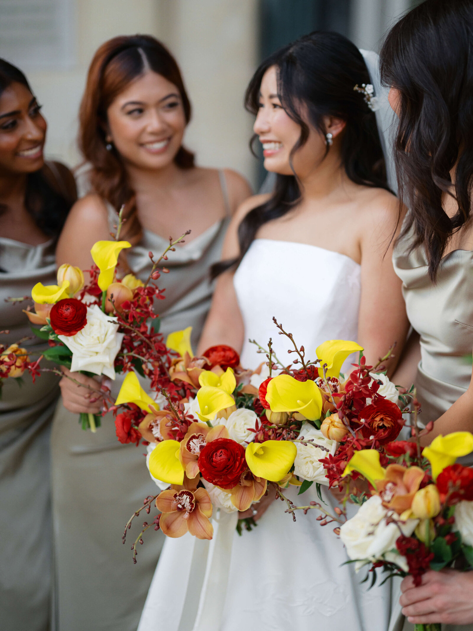 A beautiful bride carries red and yellow flowers during her wedding in an image by Virginia wedding photographer