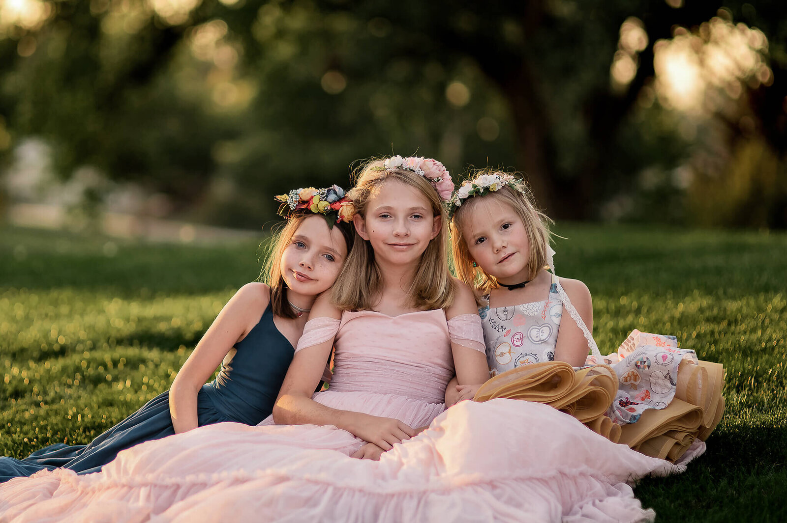 Three sisters wearing couture gowns sitting in a field near Gillette Wyoming