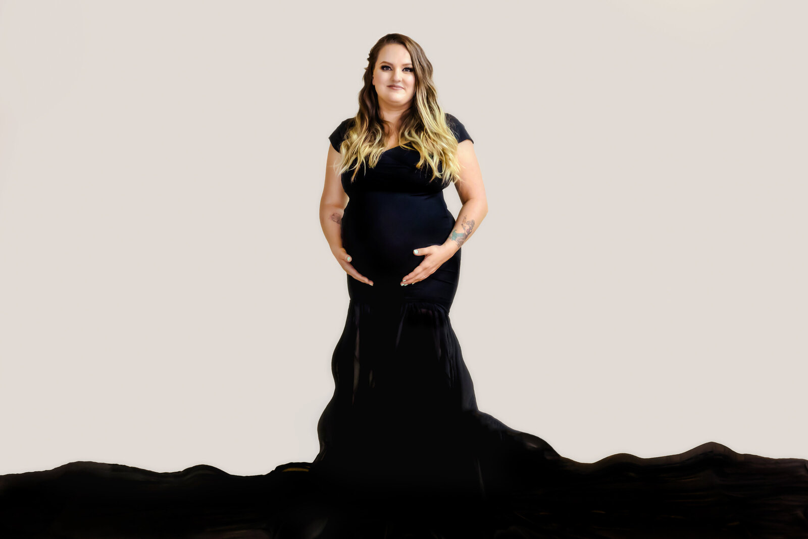 Maternity Photographer, a mother-to-be holds her belly in a black gown with a long train