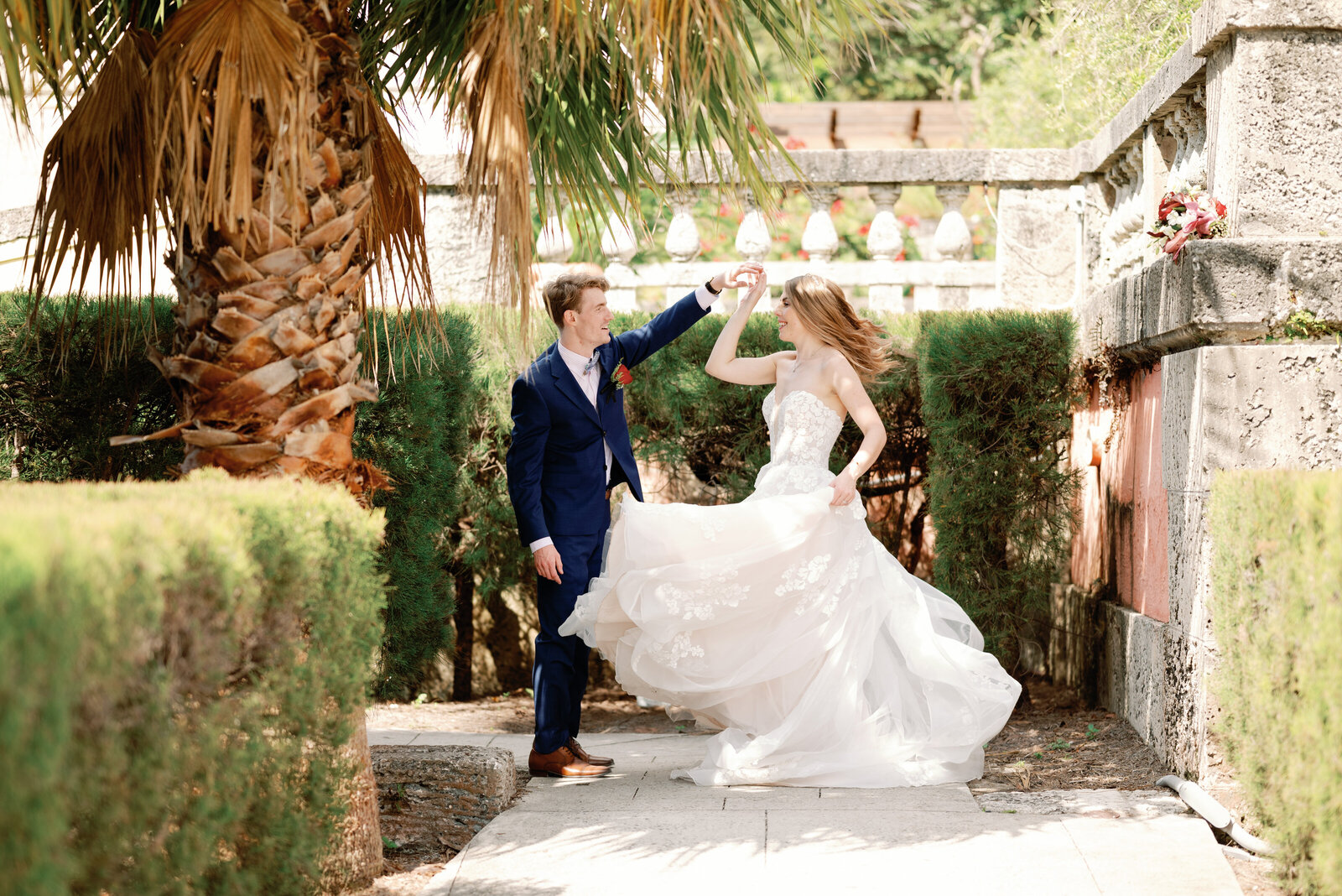 Groom twirling bride on a shaded walkway