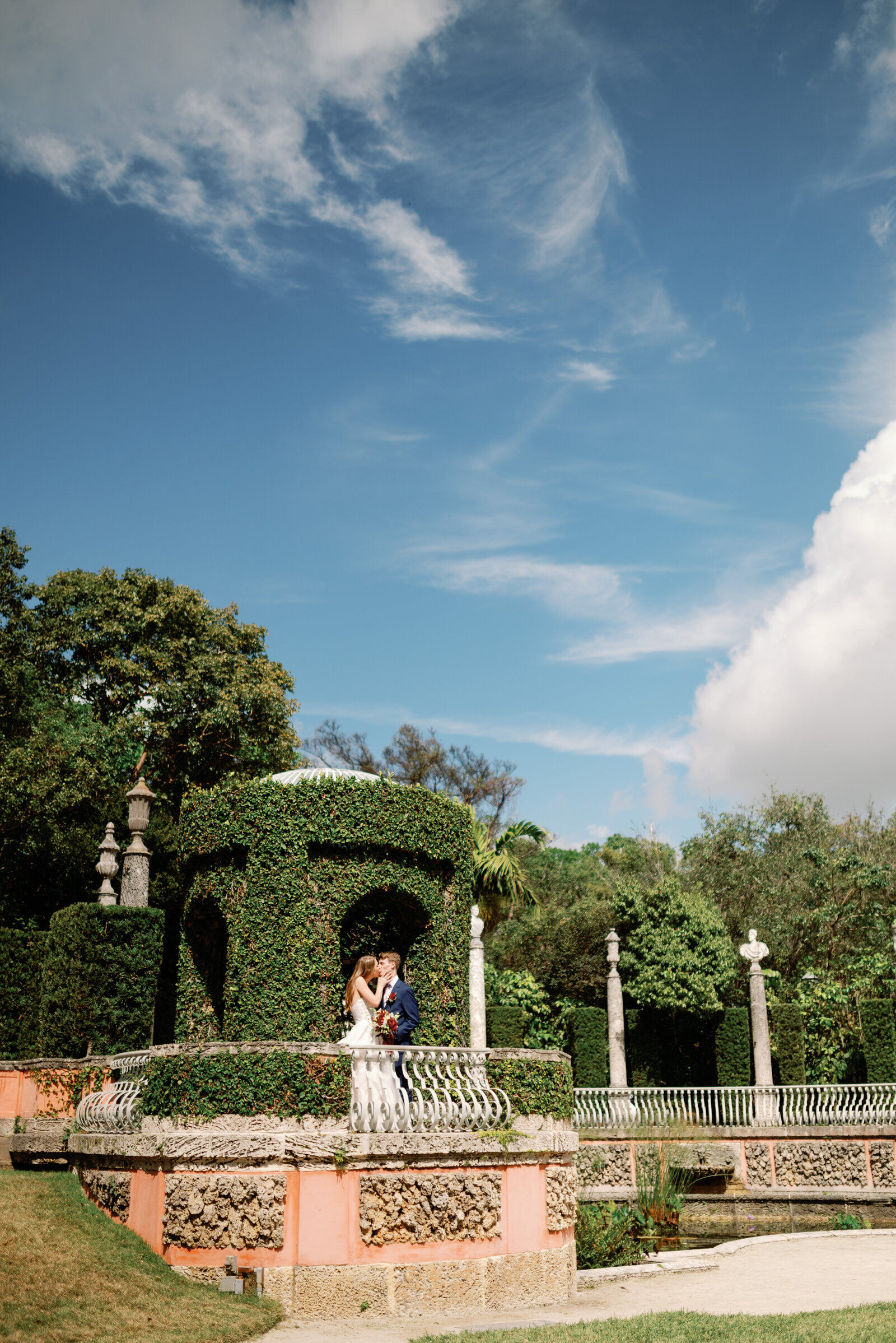 Wide view of bride and groom in an ivy covered garden tower