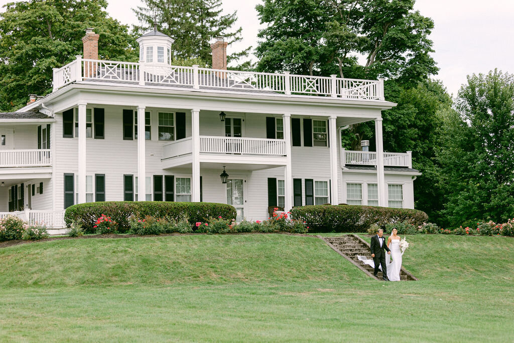 white historic home with rose gardens and bride and father descending the stone steps