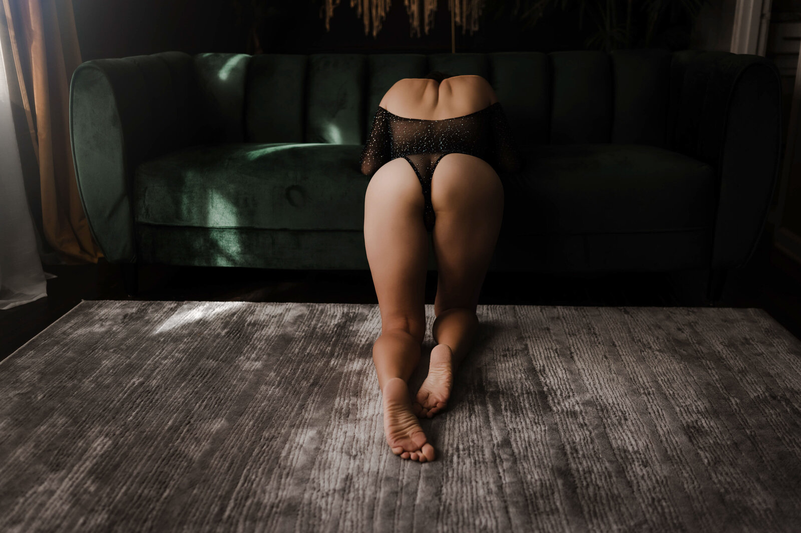 An image from Boudoir Photography in Memphis of a woman kneeling on the floor and leaning on a couch in mesh lingerie