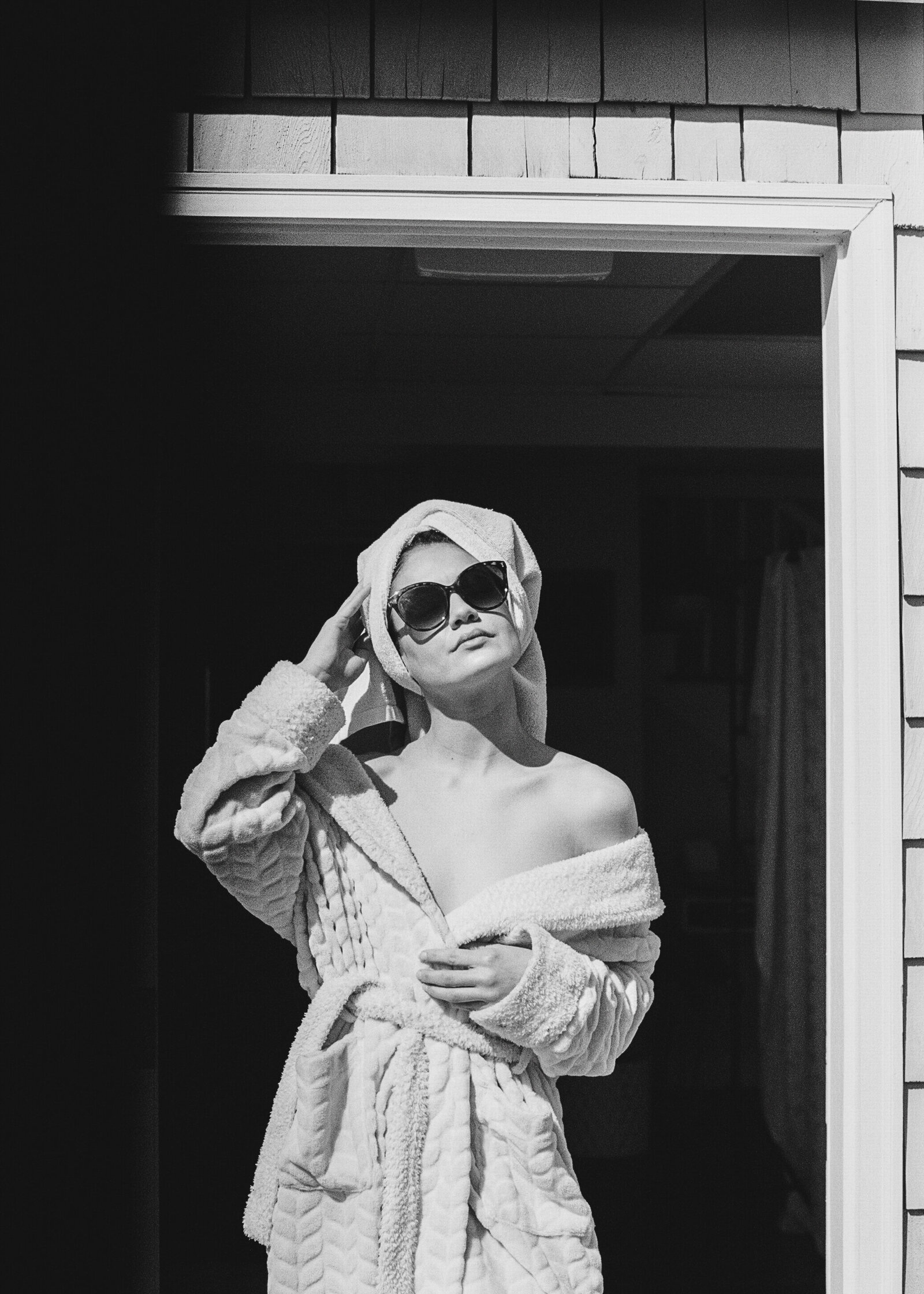 Black and white boudoir photo of woman wearing bathrobe and sunglasses