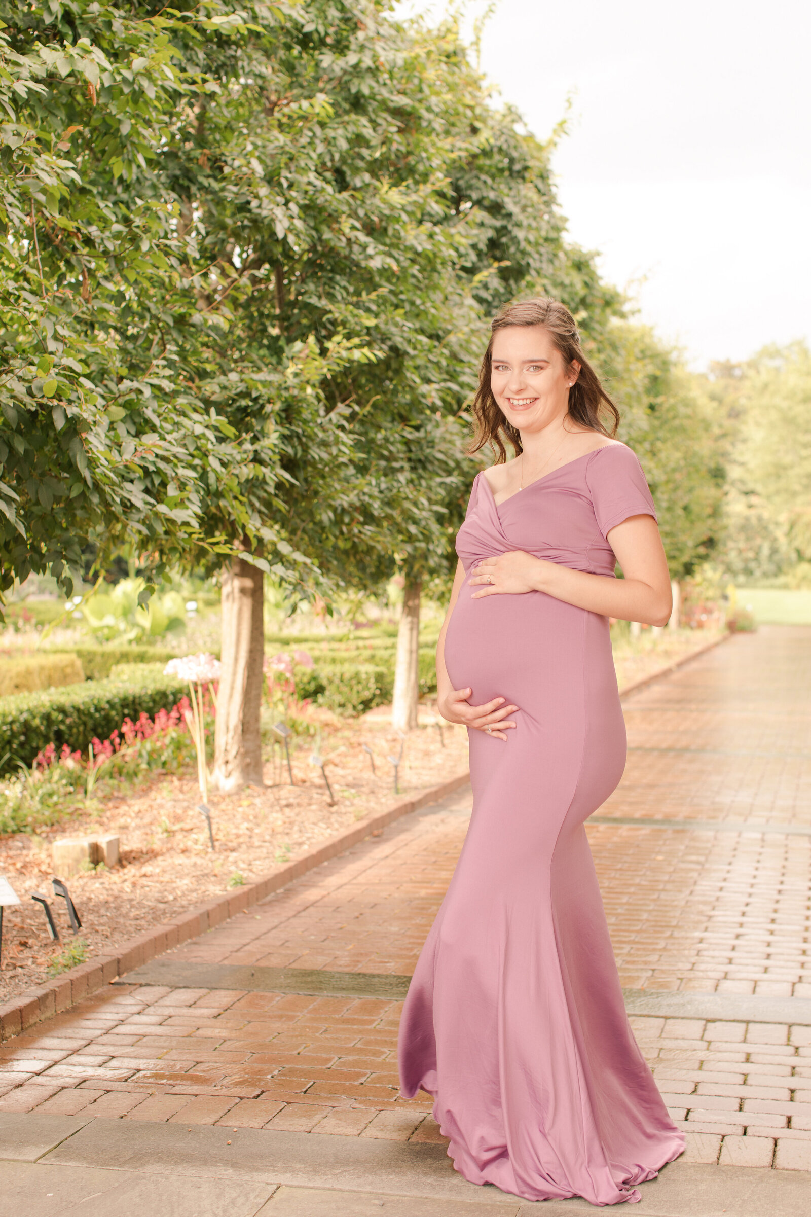 maternity portrait of woman in a garden in lilac dress