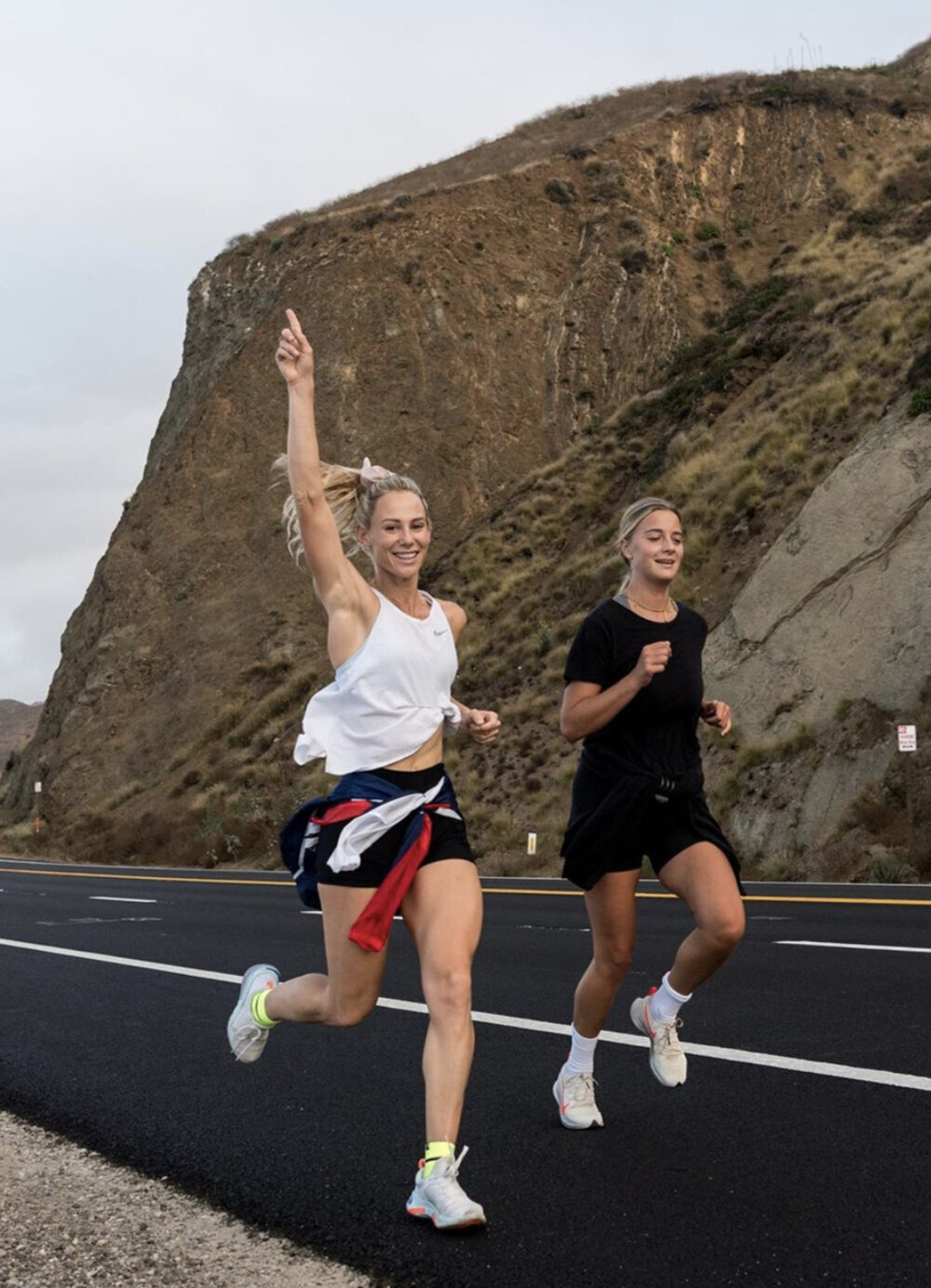 Two HER Sports Club members running together on a coastal road during marathon training.