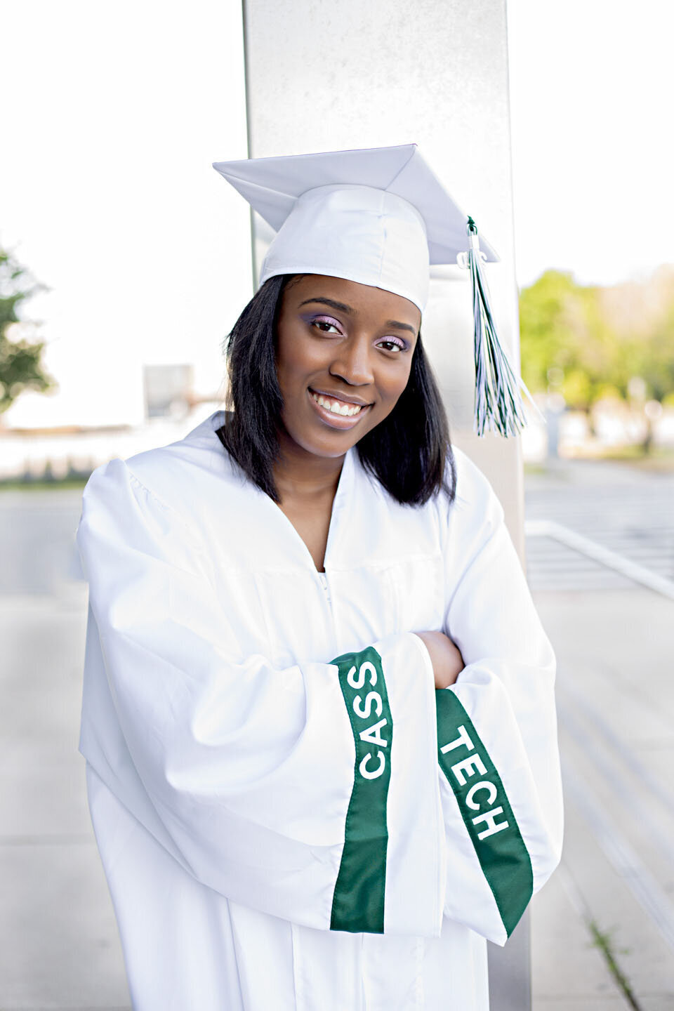 Senior girl with black hair with white cap and gown outside at Cass Tech High School in Detroit, Michigan
