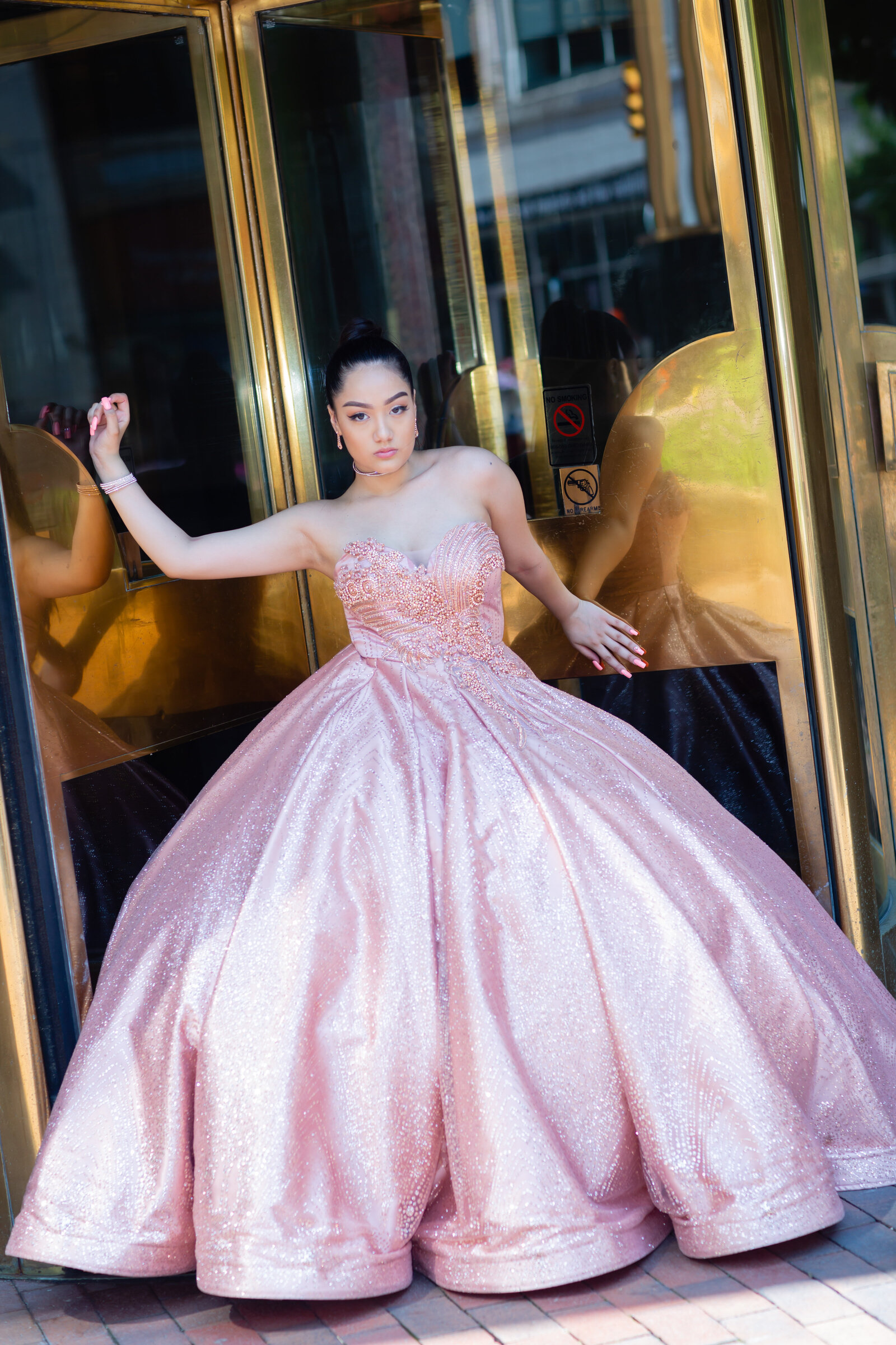 Rosalyn Kinsey posing gracefully in her quinceañera gown at the golden doors of Playhouse Square in Cleveland, Ohio, a perfect blend of elegance and sophistication.