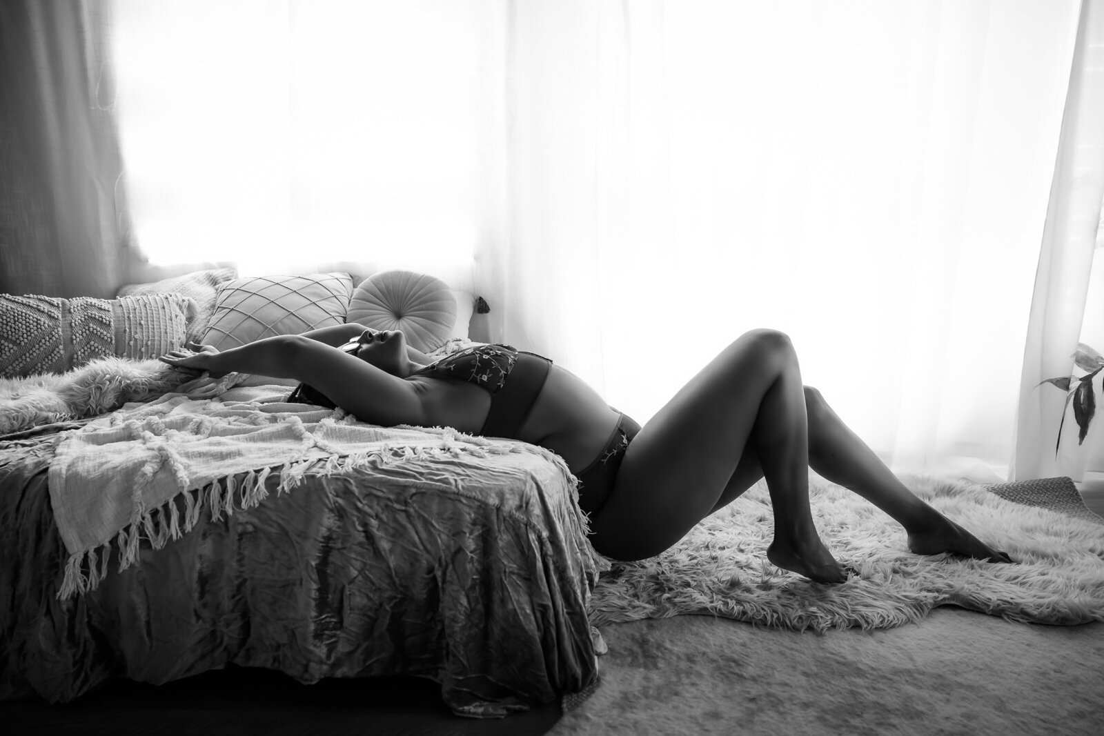 Full body black and white image of woman l;aying on her back with her legs extendedin front of her