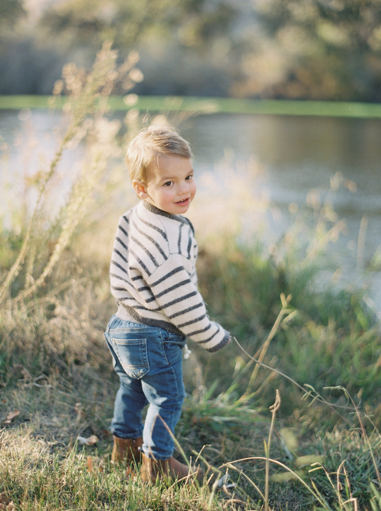 sweet little boy beside a stream holding a fishing line