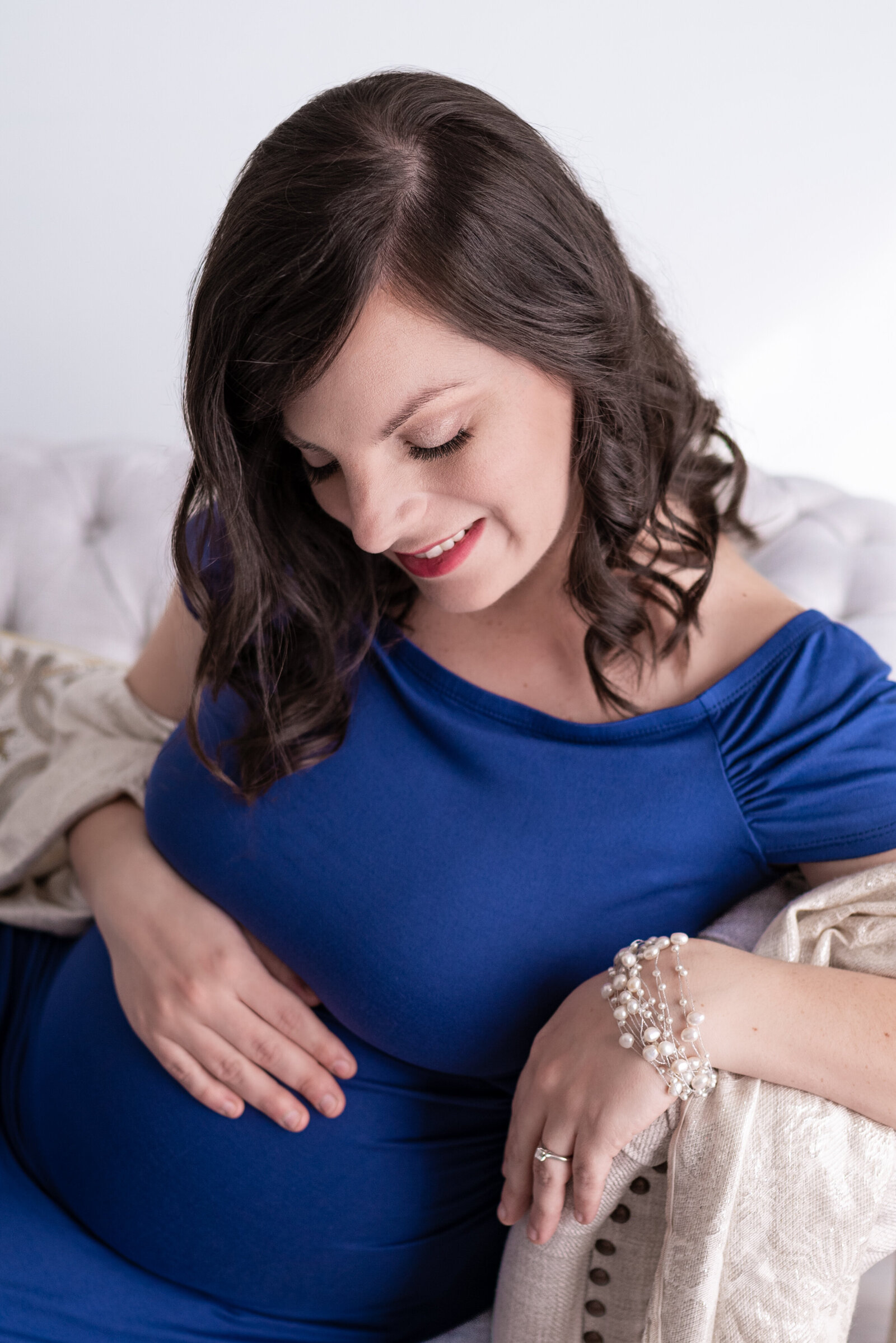 A pregnant woman smiling at her stomach in her Huntsville Alabama studio maternity portraits