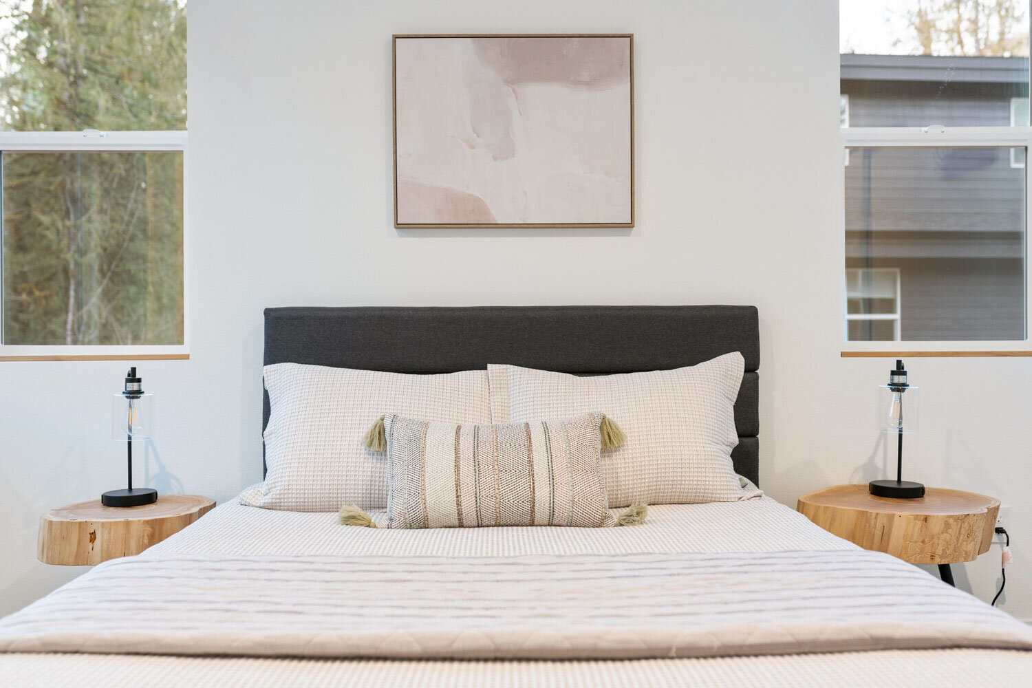 A cozy modern bedroom with a grey upholstered bed and wooden side tables